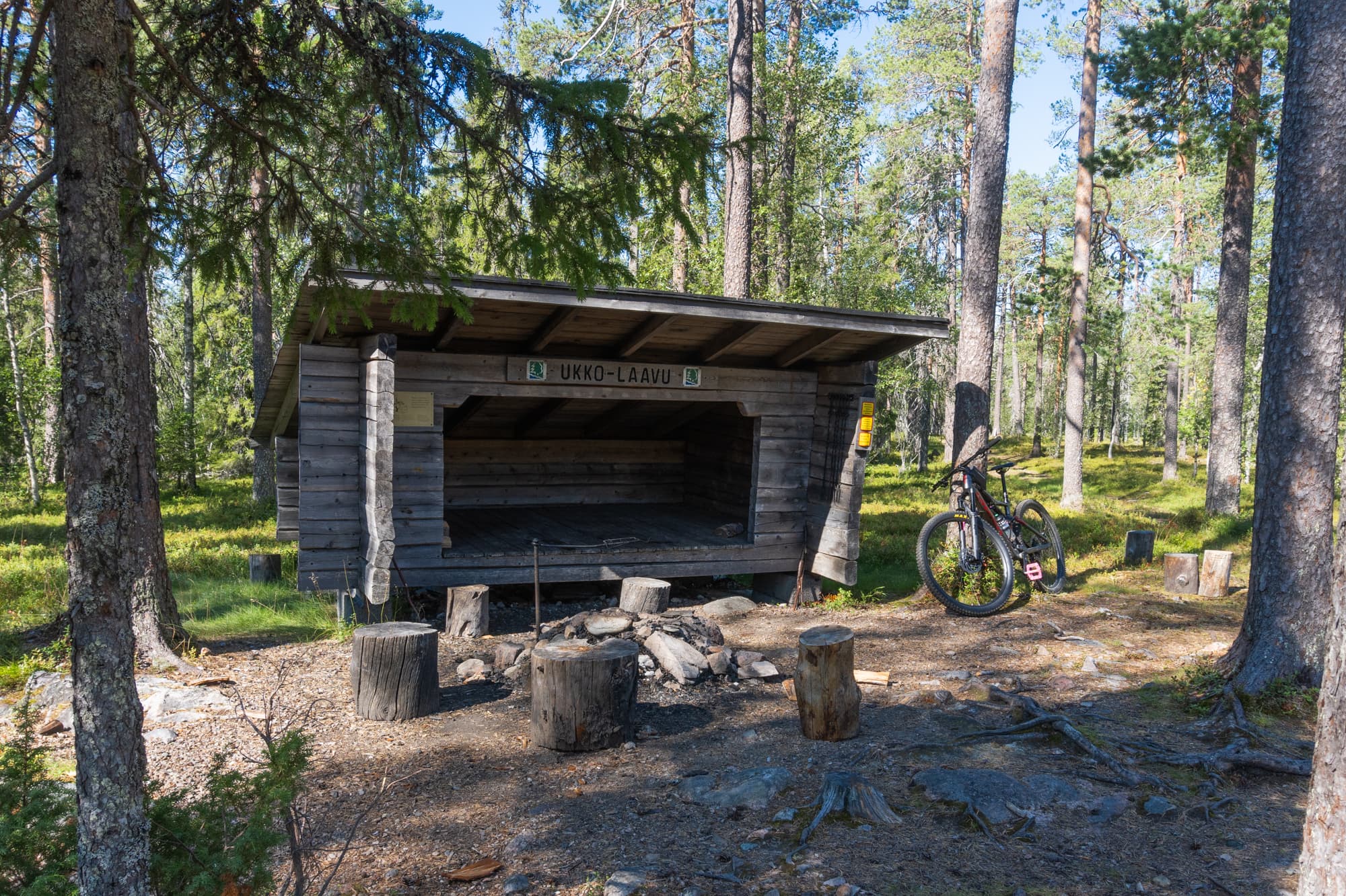 Laavun edessä on tulipaikka ja pöllejä.