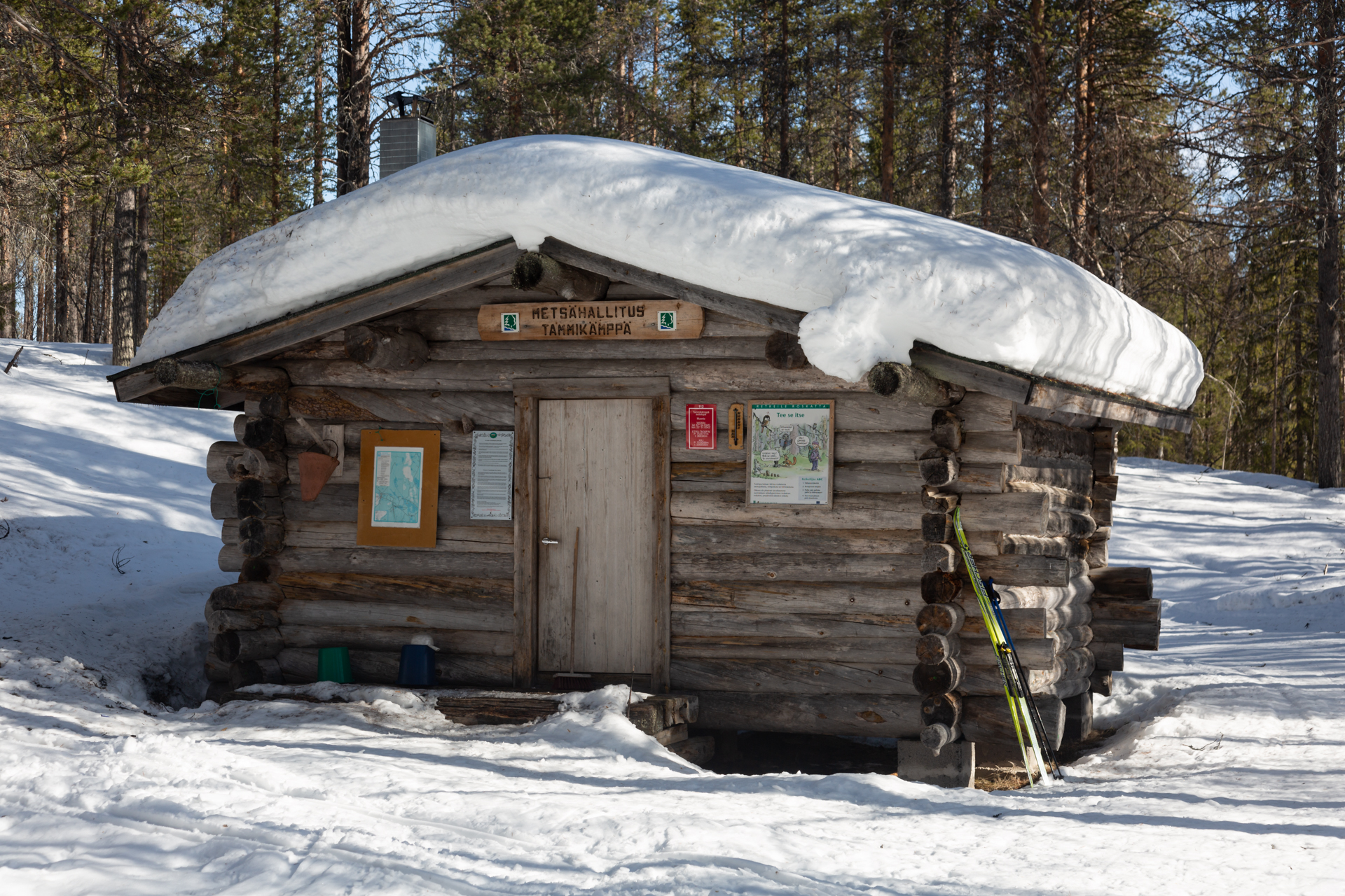 A round log cabin in a snowy forest landscape.