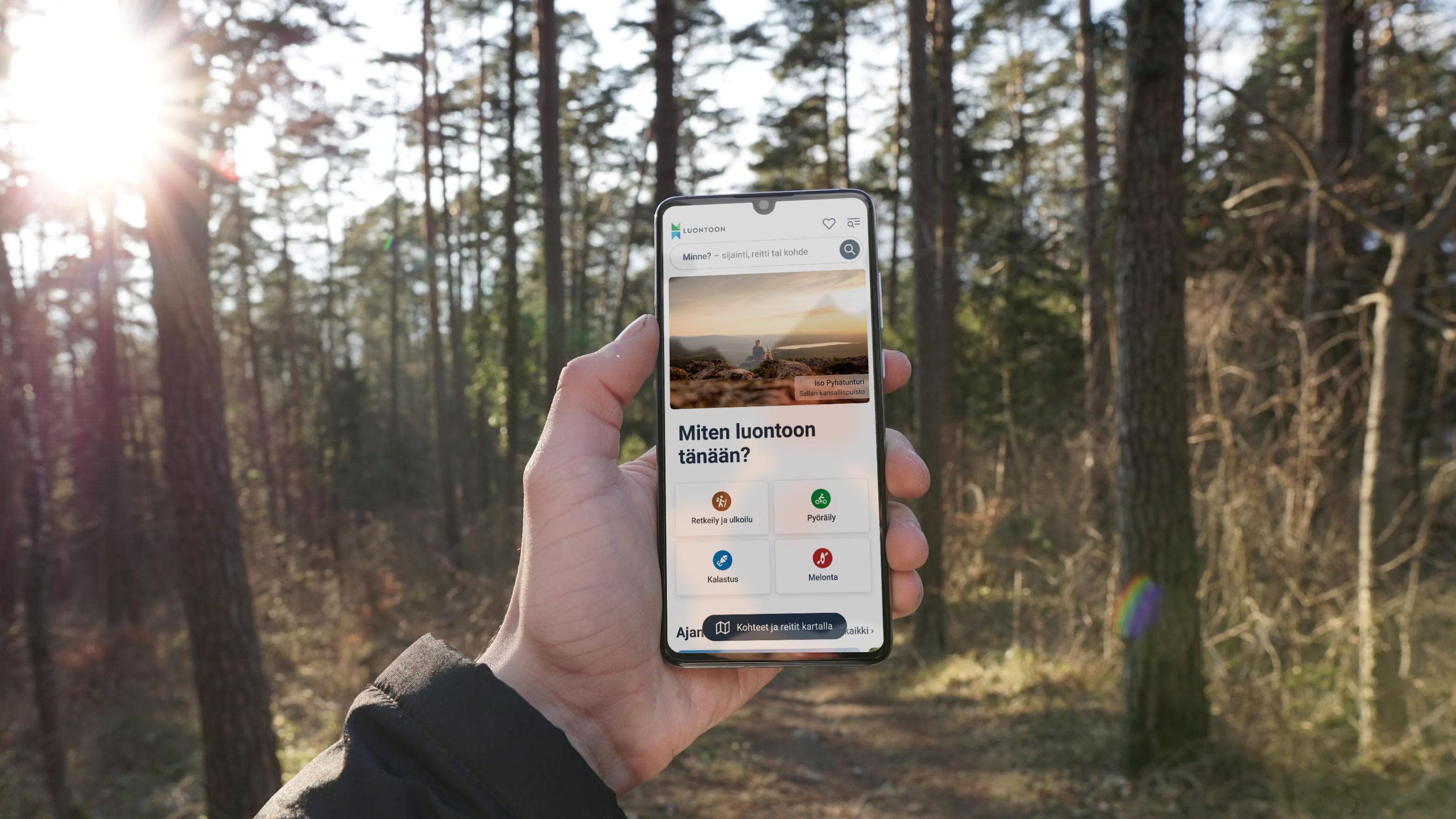 Kännykkä kädellä. Kännykässä näkyy uusi Luontoon-palvelu.