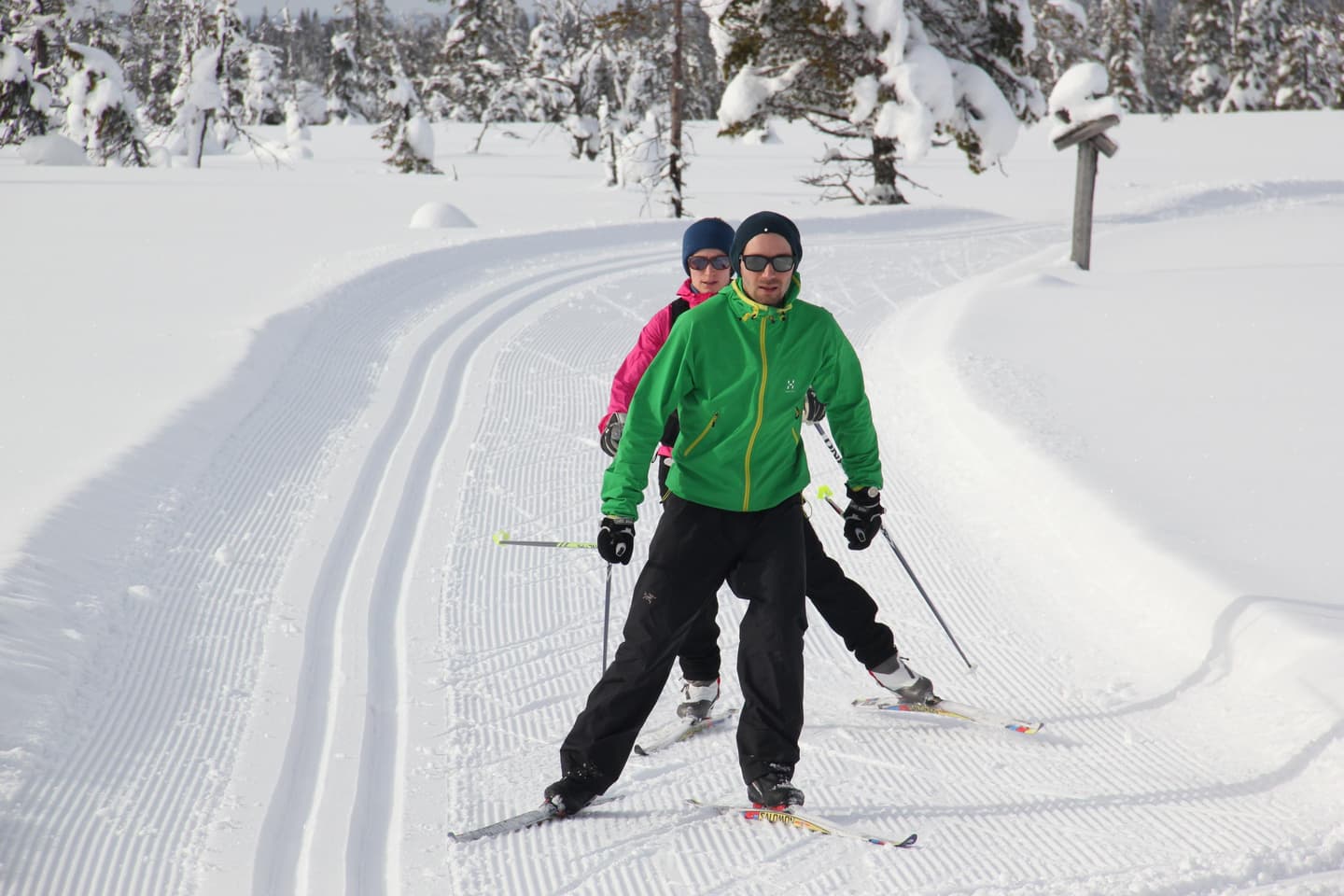 Two skiers skating next to the skitrack.