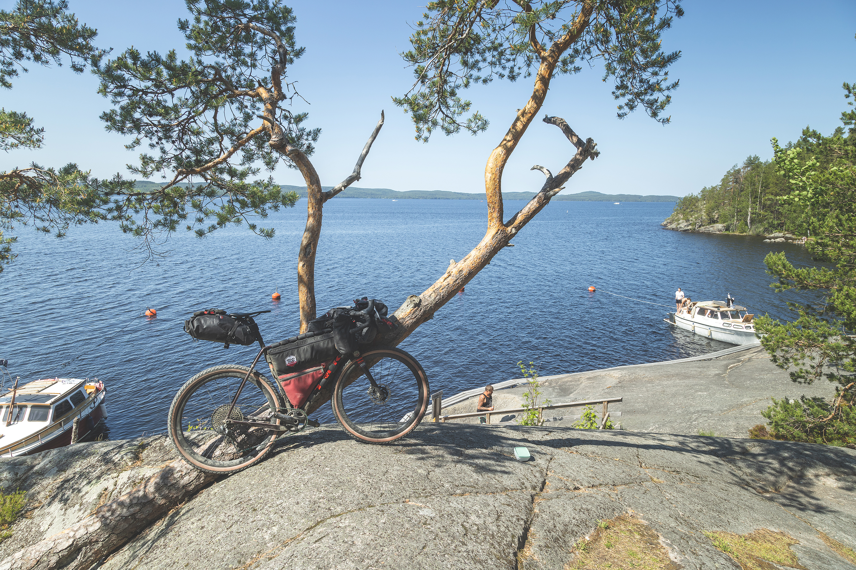 Gravel pyörä nojaamassa puuhun kalliolla järven rannalla.