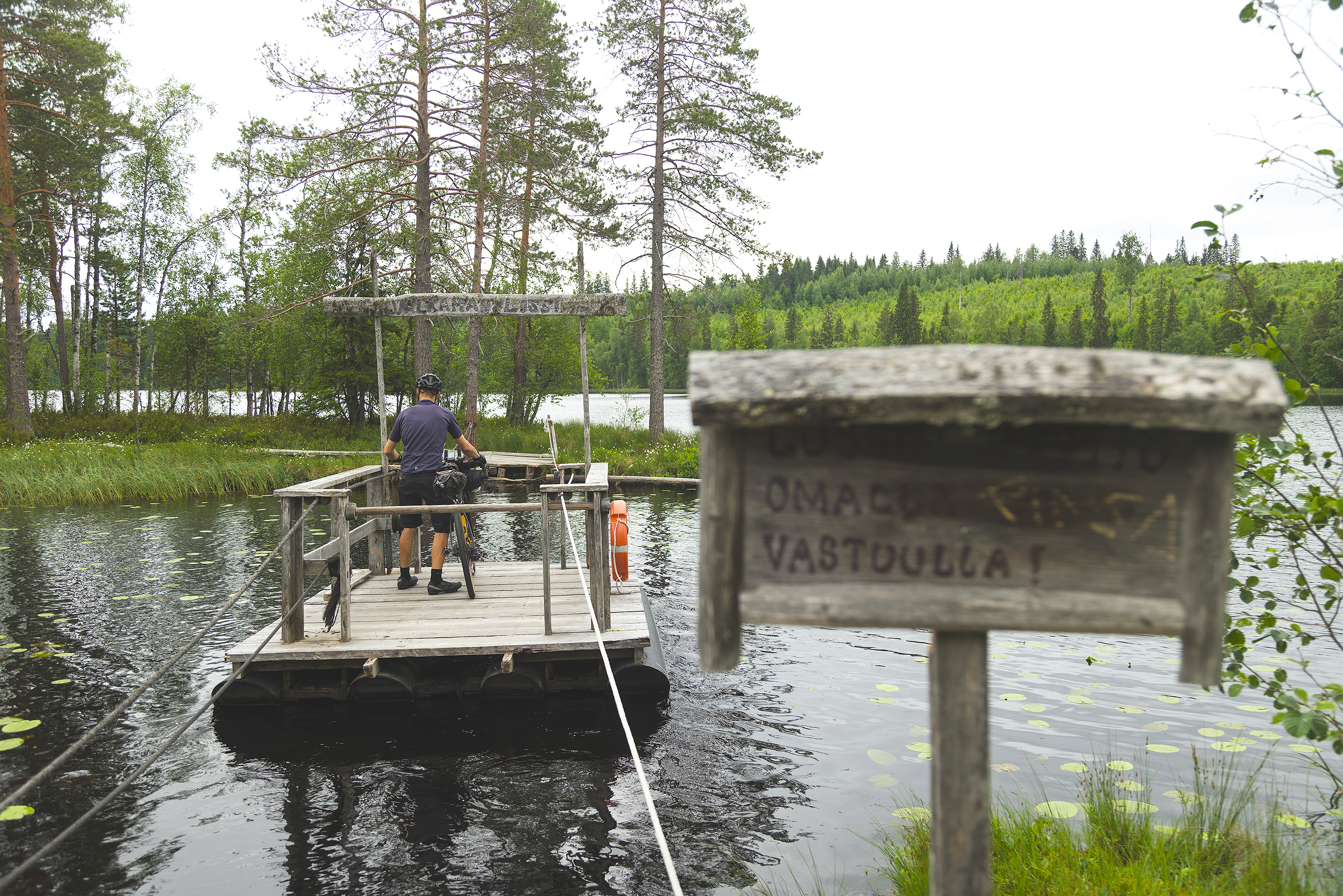Henkilö siirtymässä pyörän kanssa köysilossilla laavusaareen.