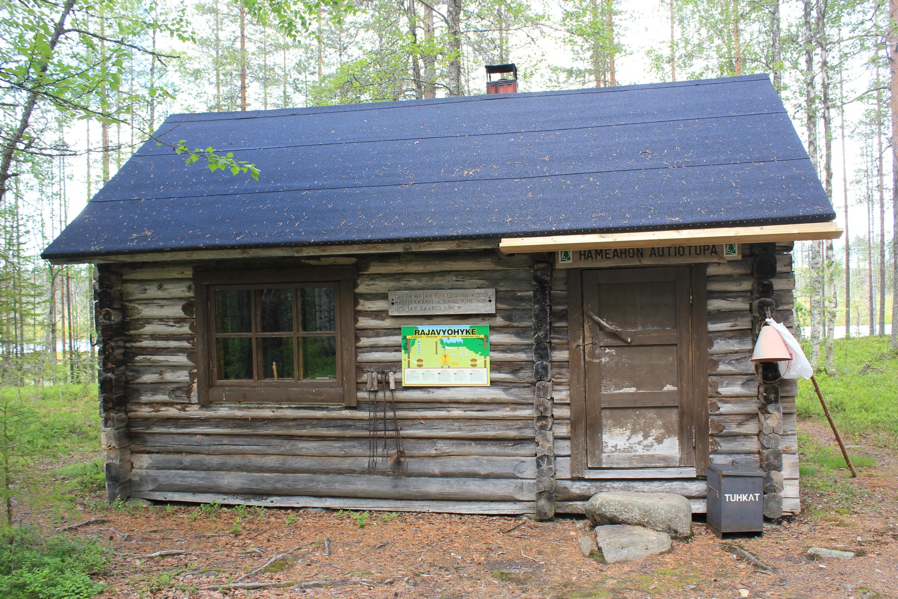 In the middle, a modest cabin with one window on the left side. Forest in the background.