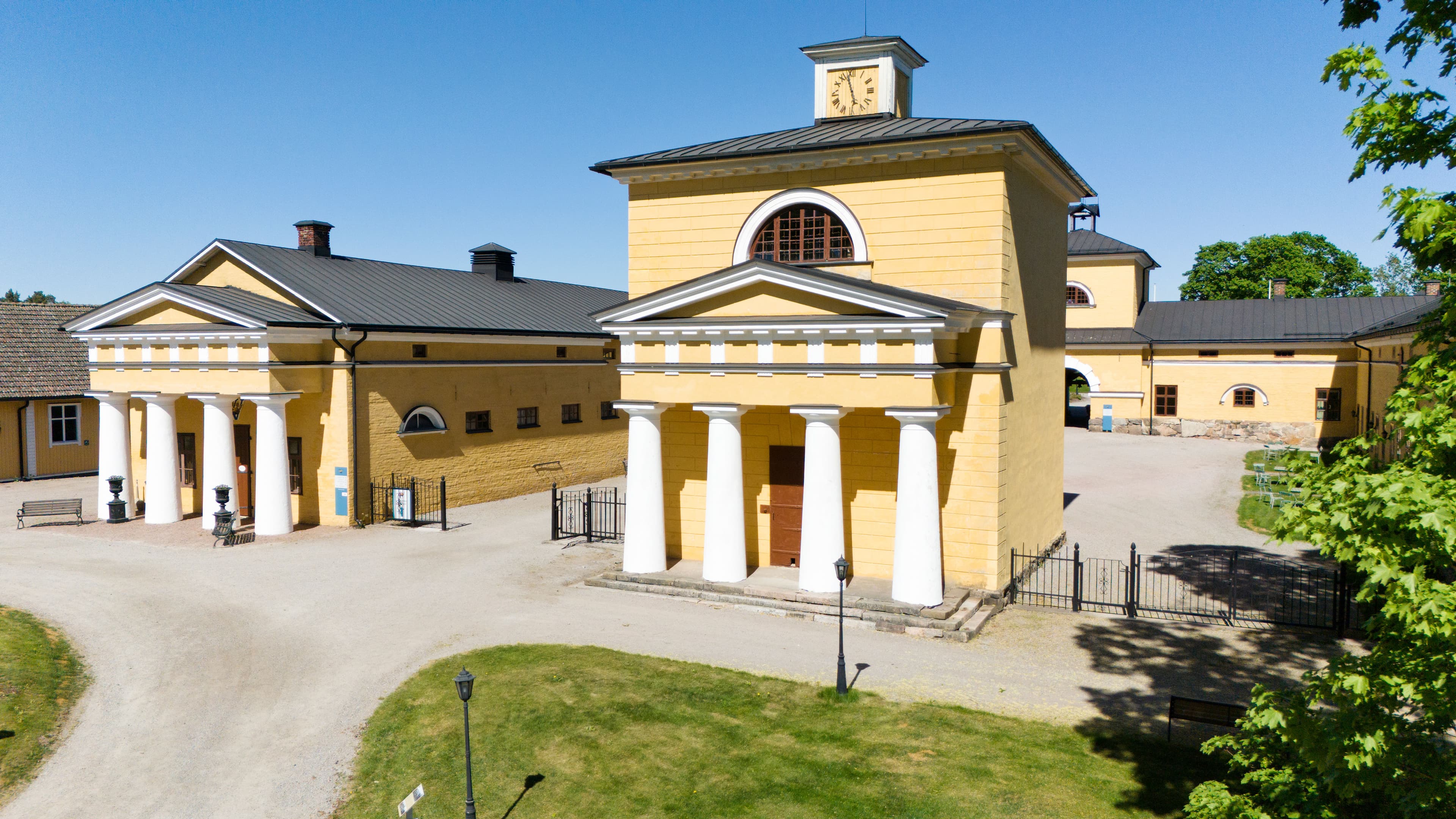 Kuva yläviistosta Wiurilan kartanon keltaisesta rakennuksesta, jossa valkoiset pylväät.