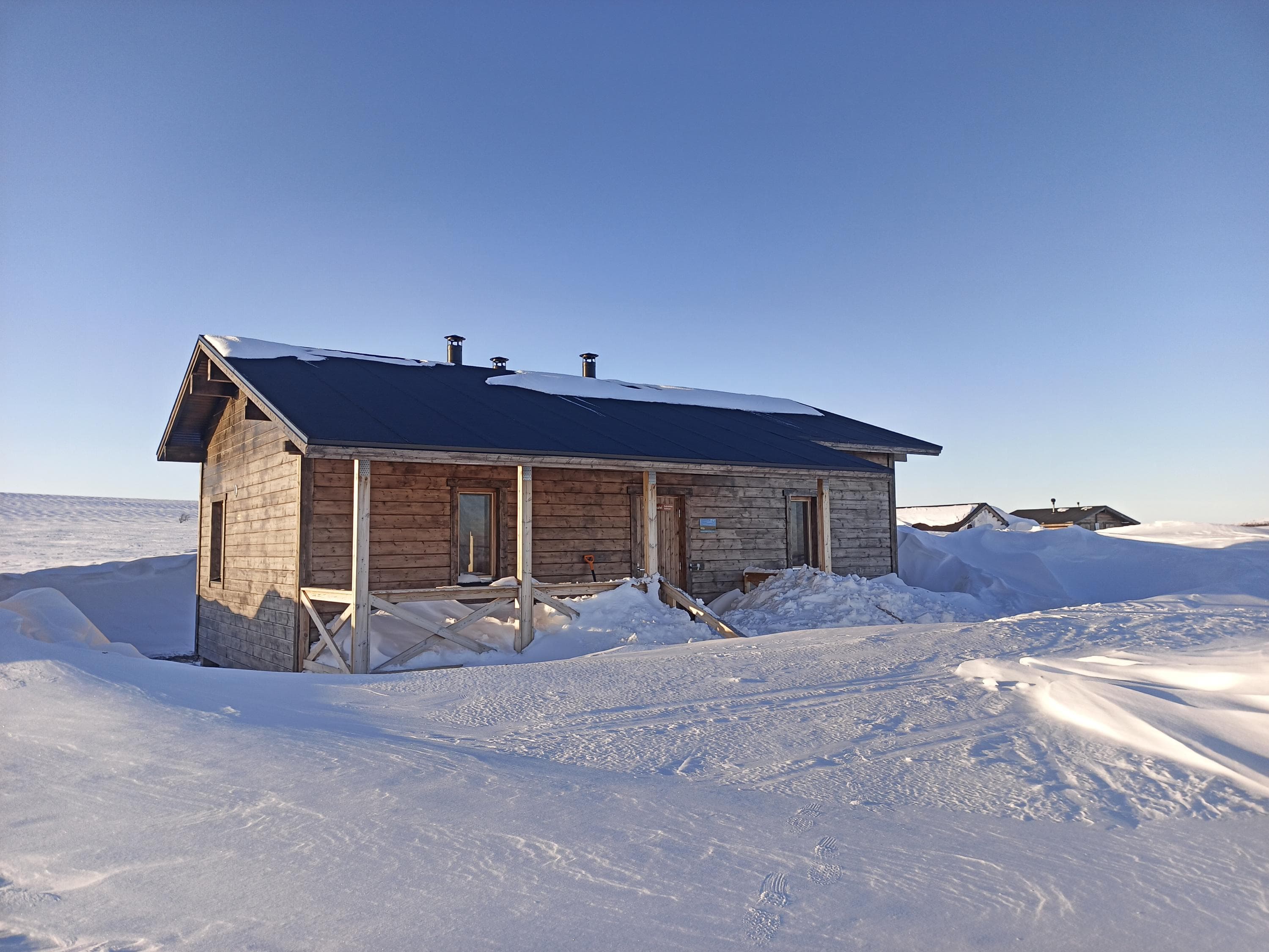 The light-colored cabin is newly built and located in the open fell.