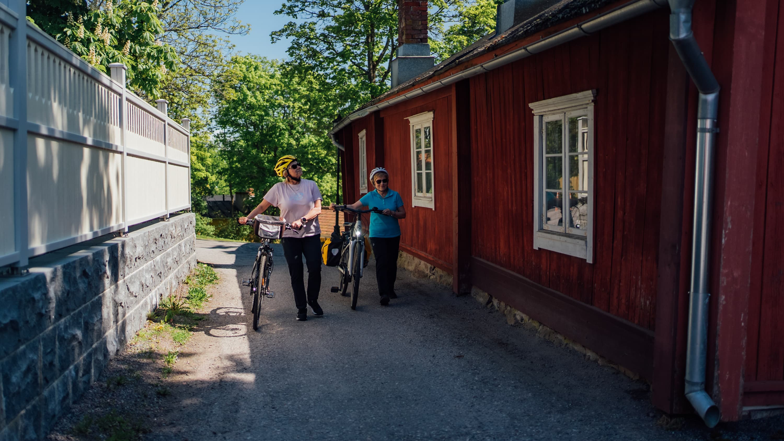 Pyöräilijät kävelemässä puutalokorttelien välissä