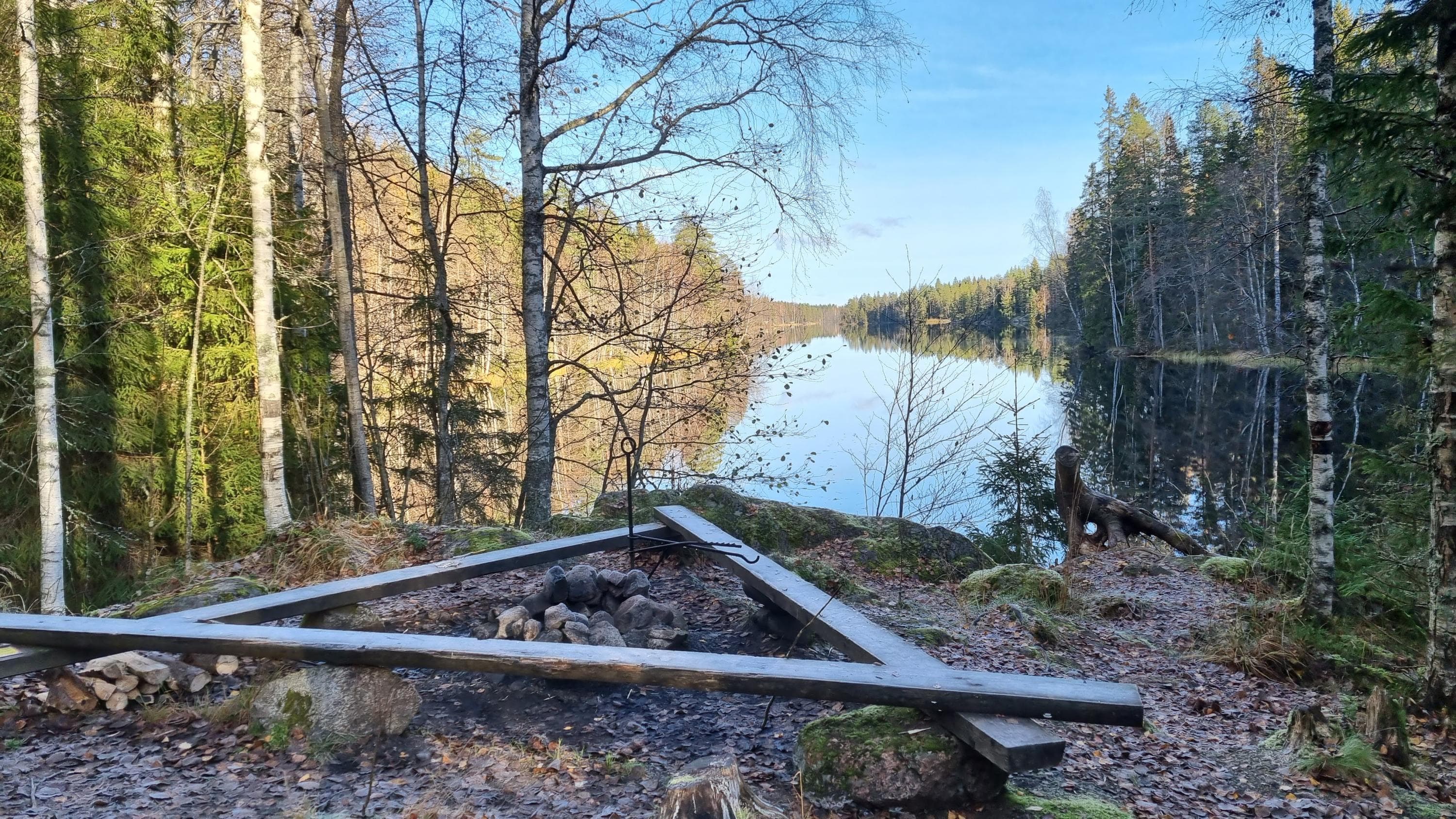  A campfire site made of stones by the shore of a pond.