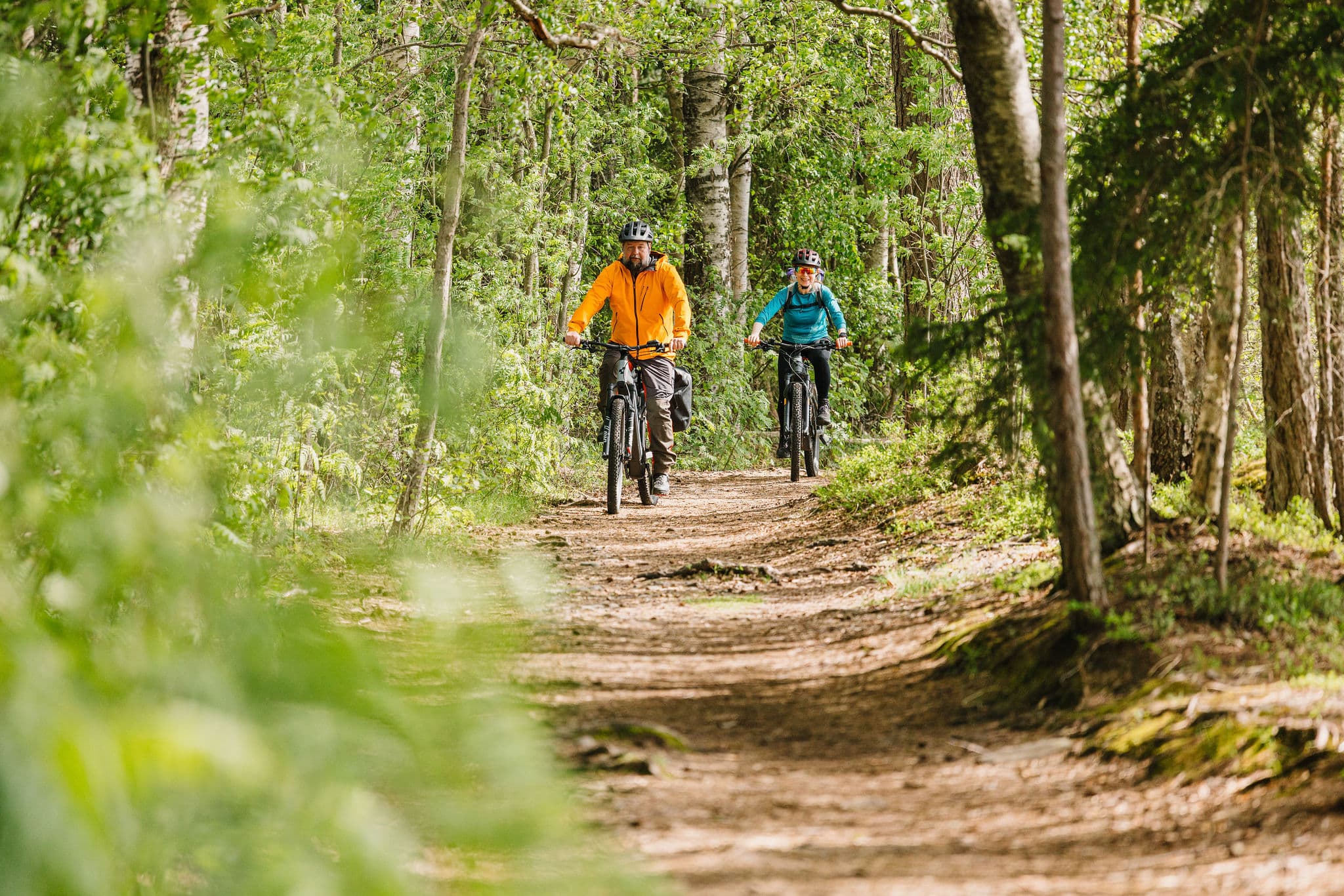 Kaksi pyöräilijää metsässä.