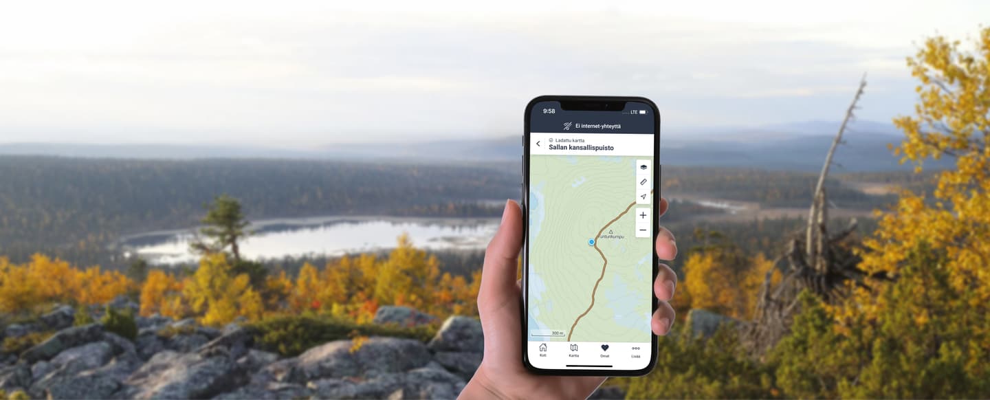 Käsi, jossa on kännykkä ja siinä näkyy Luontoon-sovellus. Taustalla tunturimaisemaa.