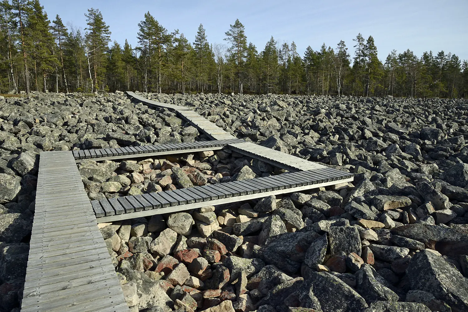 Image: Terttu Hermansson A wooden footpath built on top of the stony field. Forest in the background.