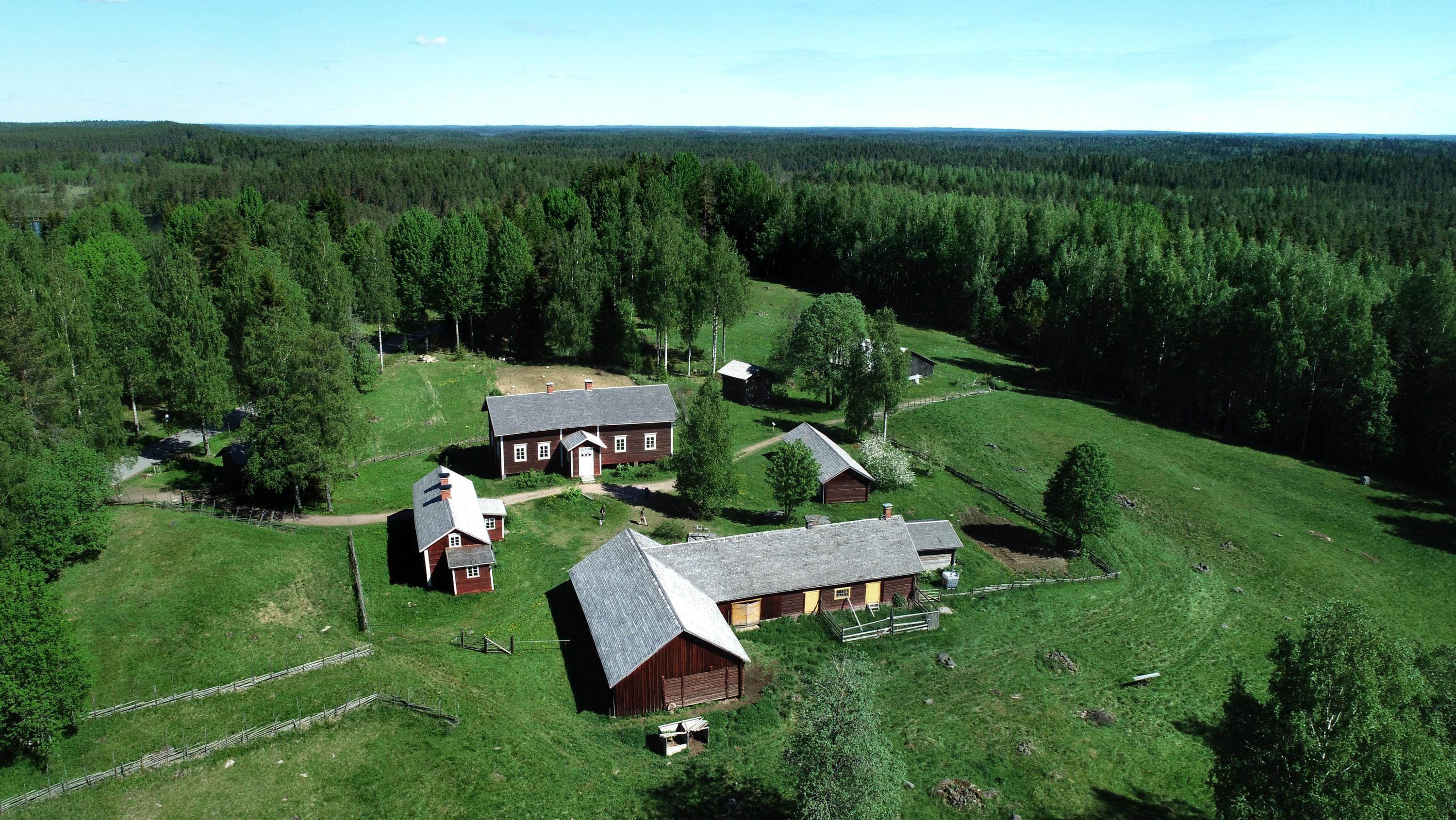Kuva: Jari Salonen Ilmakuva vanhasta maatilasta. Punaisia rakennuksia peltojen ja metsien keskellä.