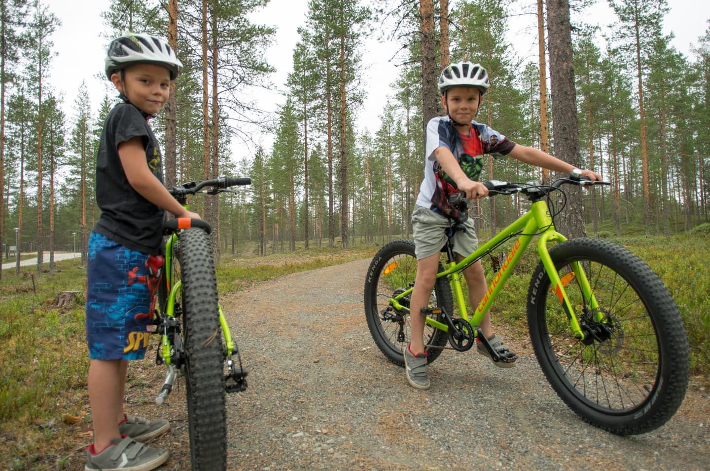 Kuva: Tuuli Turunen Kaksi poikaa maastopyörien kanssa tasaisella metsäpolulla.