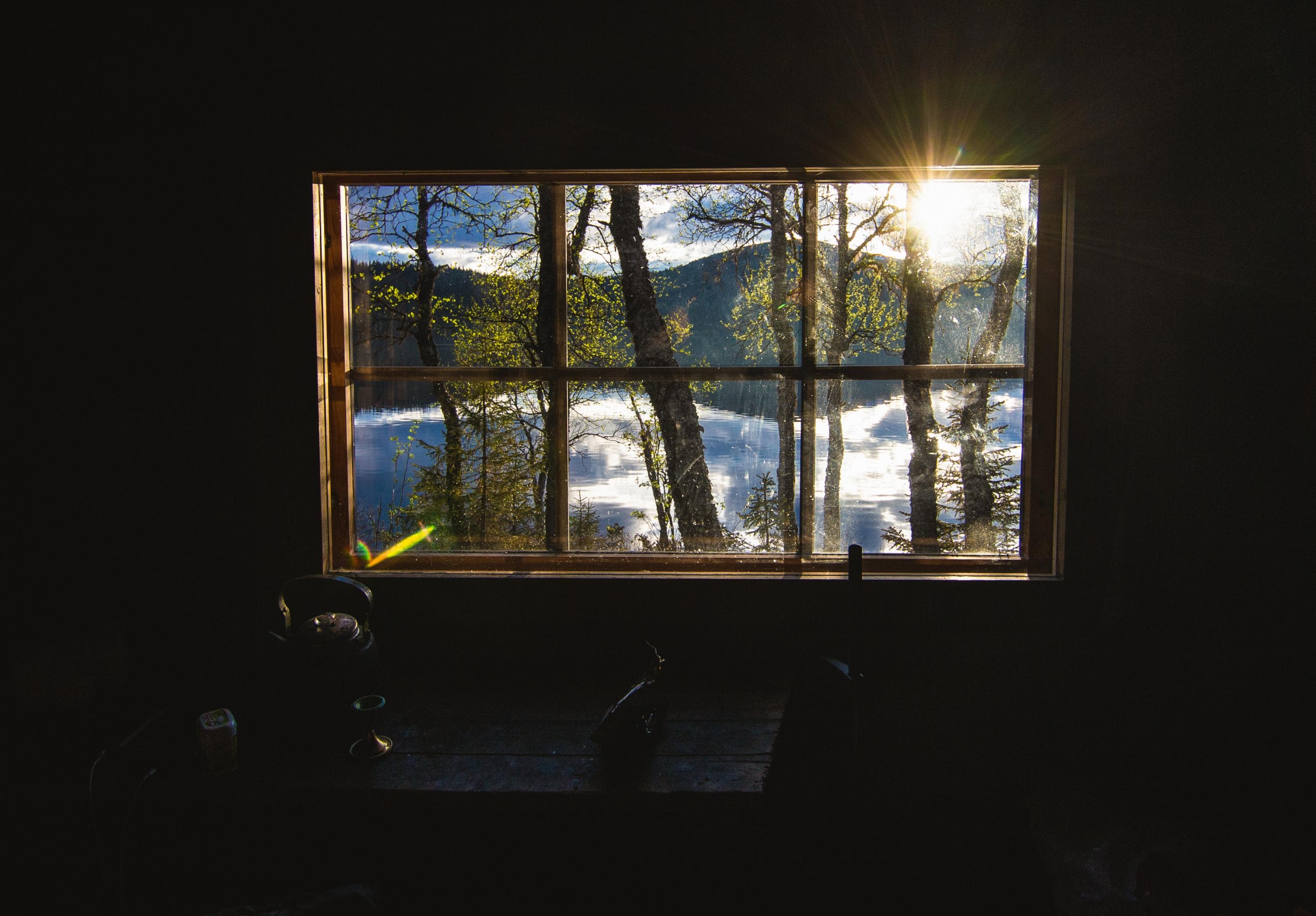 Kuva: Heikki Sulander Pimeän autiotuvan kuusiruutuisesta ikkunasta avautuu maisema järvelle ja tunturiin.