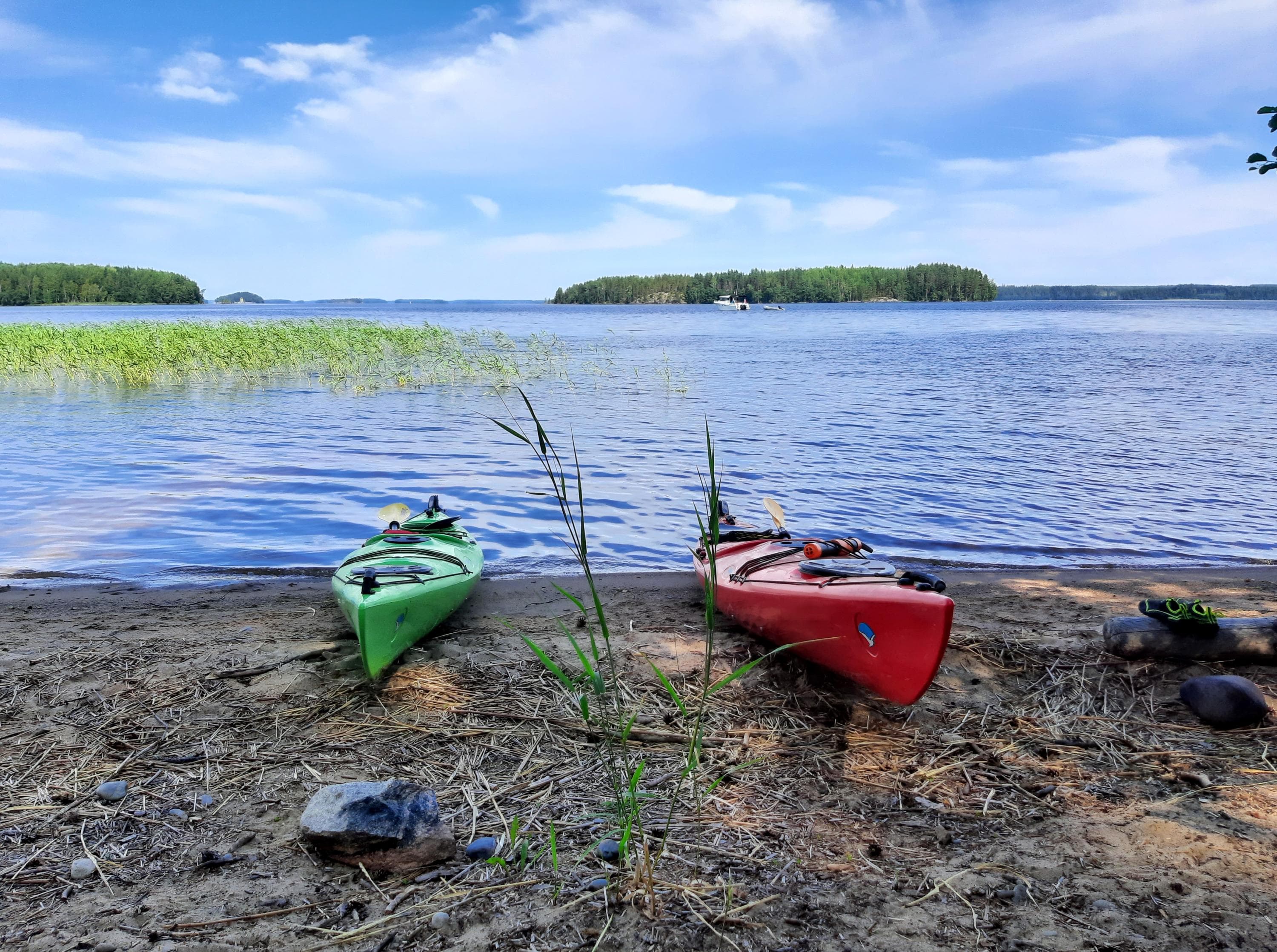 Image: Etti Kantola Two kayaks pulled ashore. Reeds are visible on the lake, and islands can be seen in the distance.