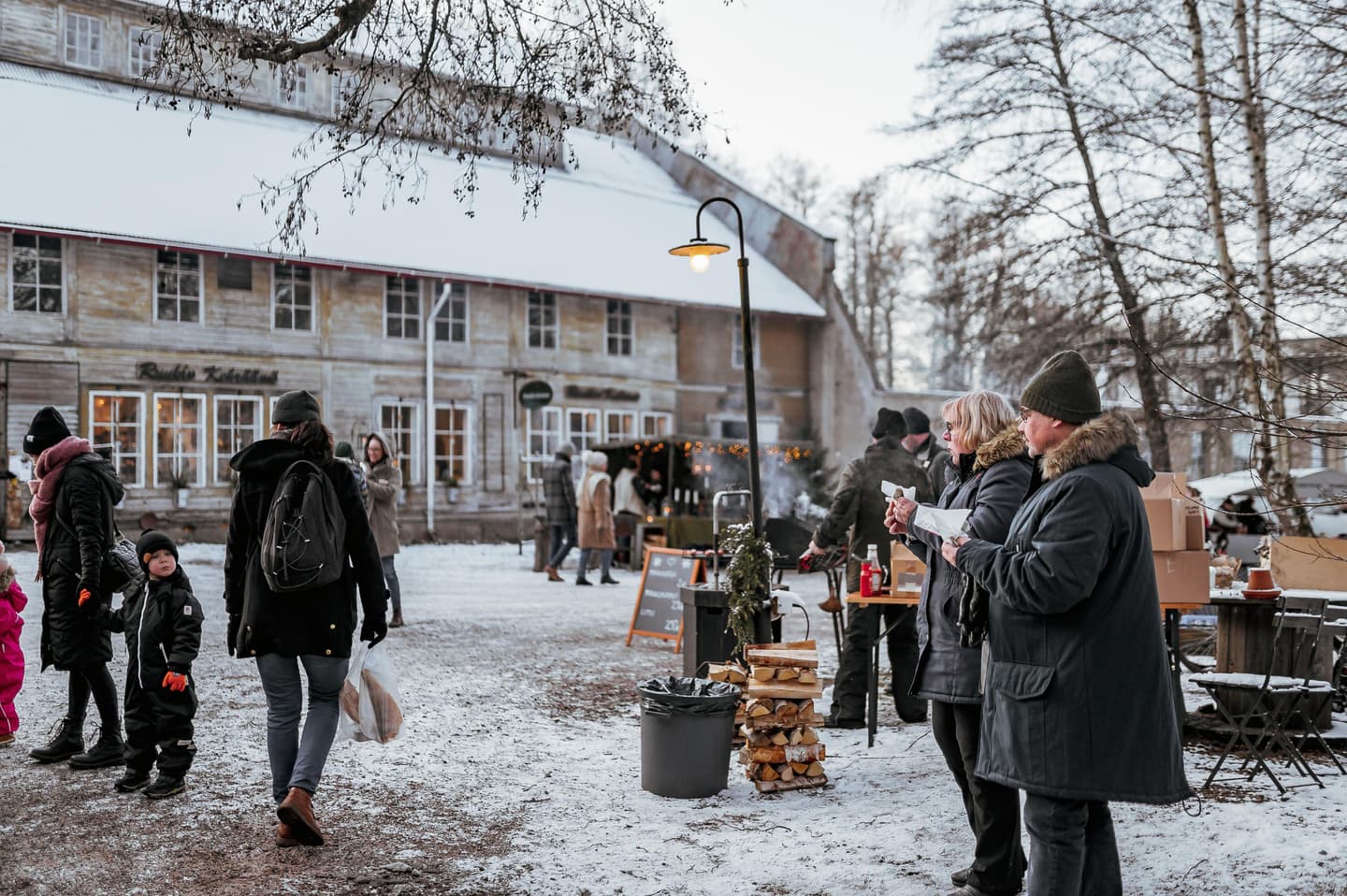 Kuva: Jasmin Yuchun Joulumarkkinat ulkona. Ihmisiä katselemassa myyntikojuja. Taustalla on valkoinen iso rakennus, maassa on lunta.
