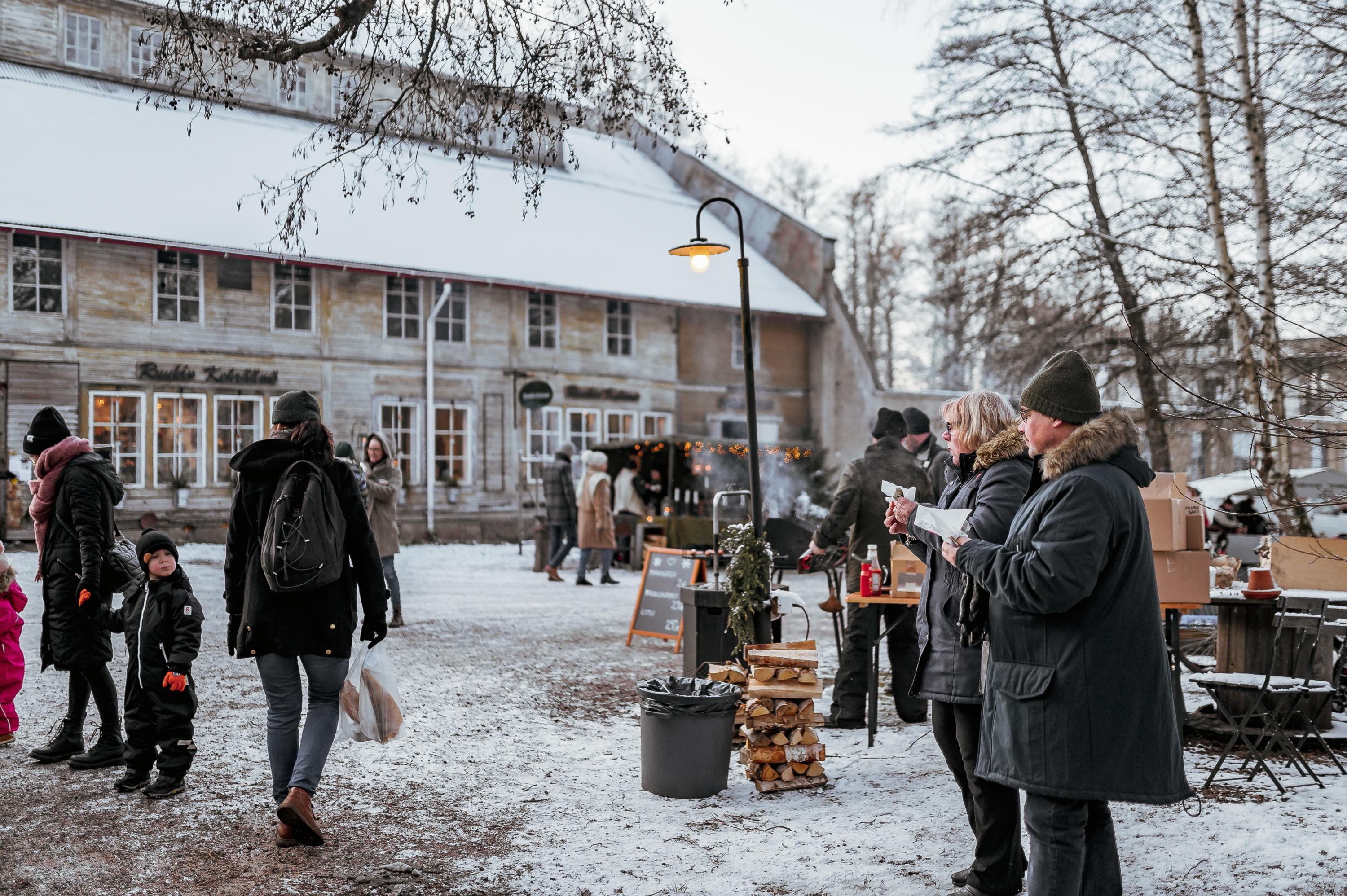 Bild: Jasmin Yuchun Utomhus julmarknad. Människor tittar på stånden. I bakgrunden finns en stor vit byggnad, och marken är täckt av snö.