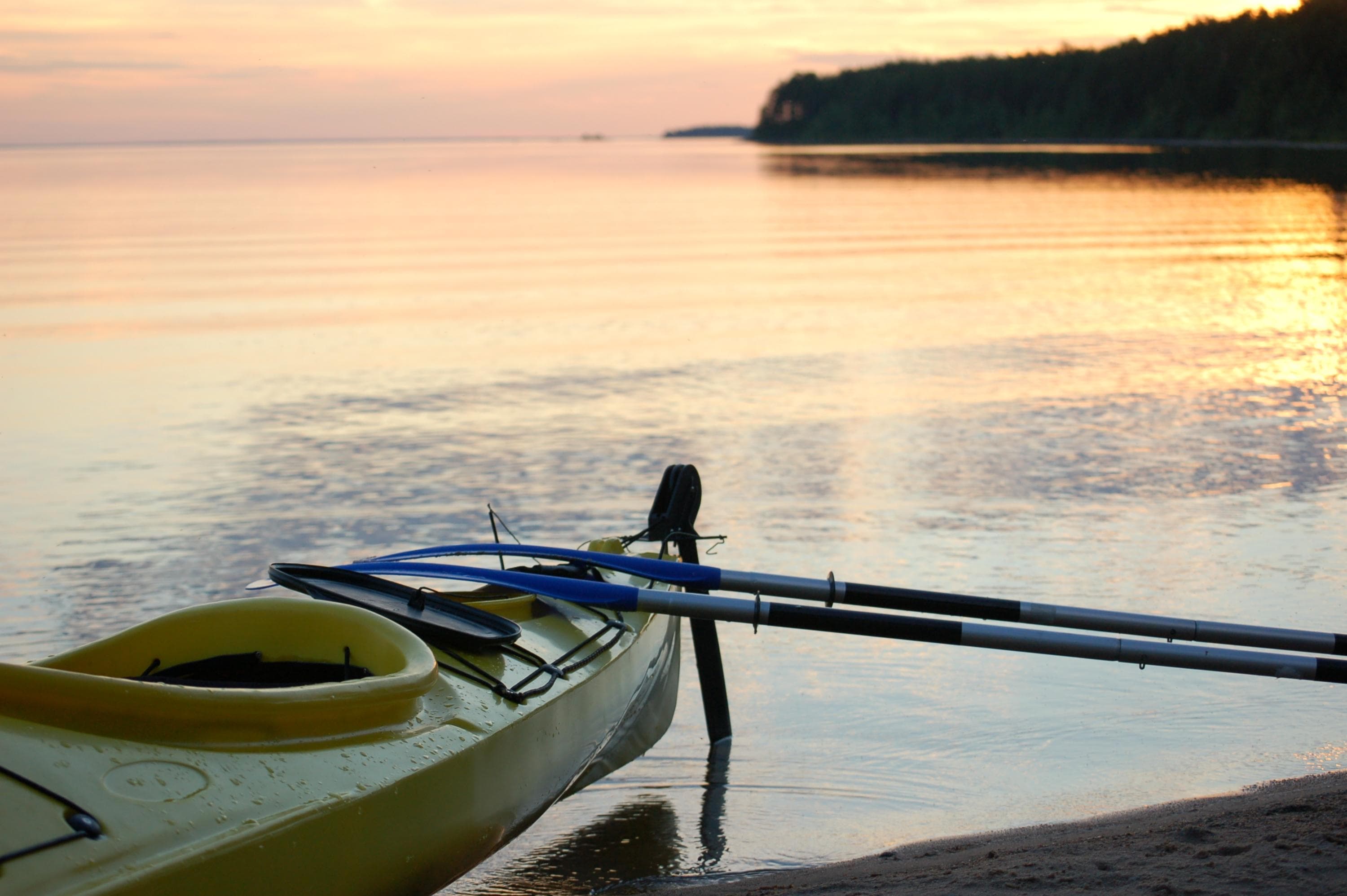 Kuva: Saara Airaksinen Etualalla on kanootti ja kaksi melaa. Taustalla tyyni järvi.