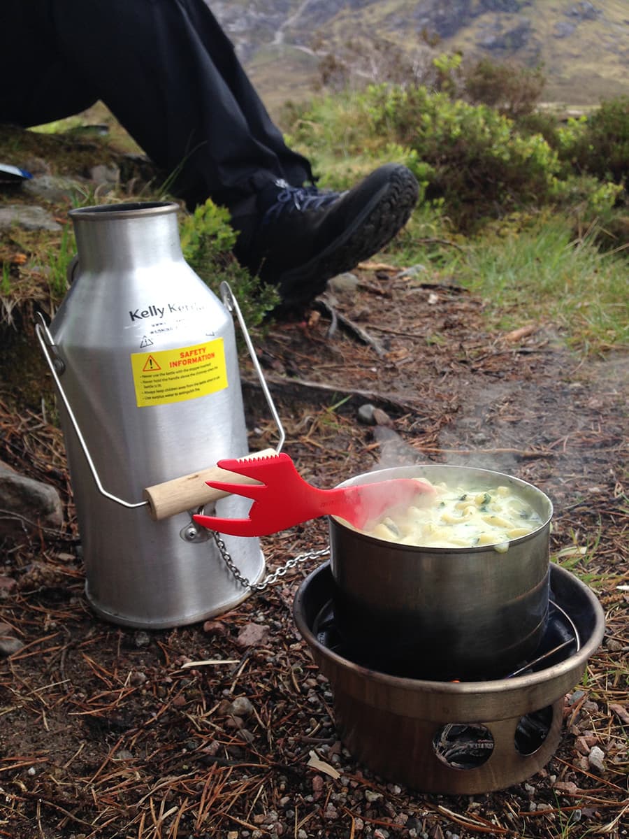Kuva: Marjo Kamäräinen Maassa on risukeitin, jonka päällä kattilassa on ruoka valmistumassa.