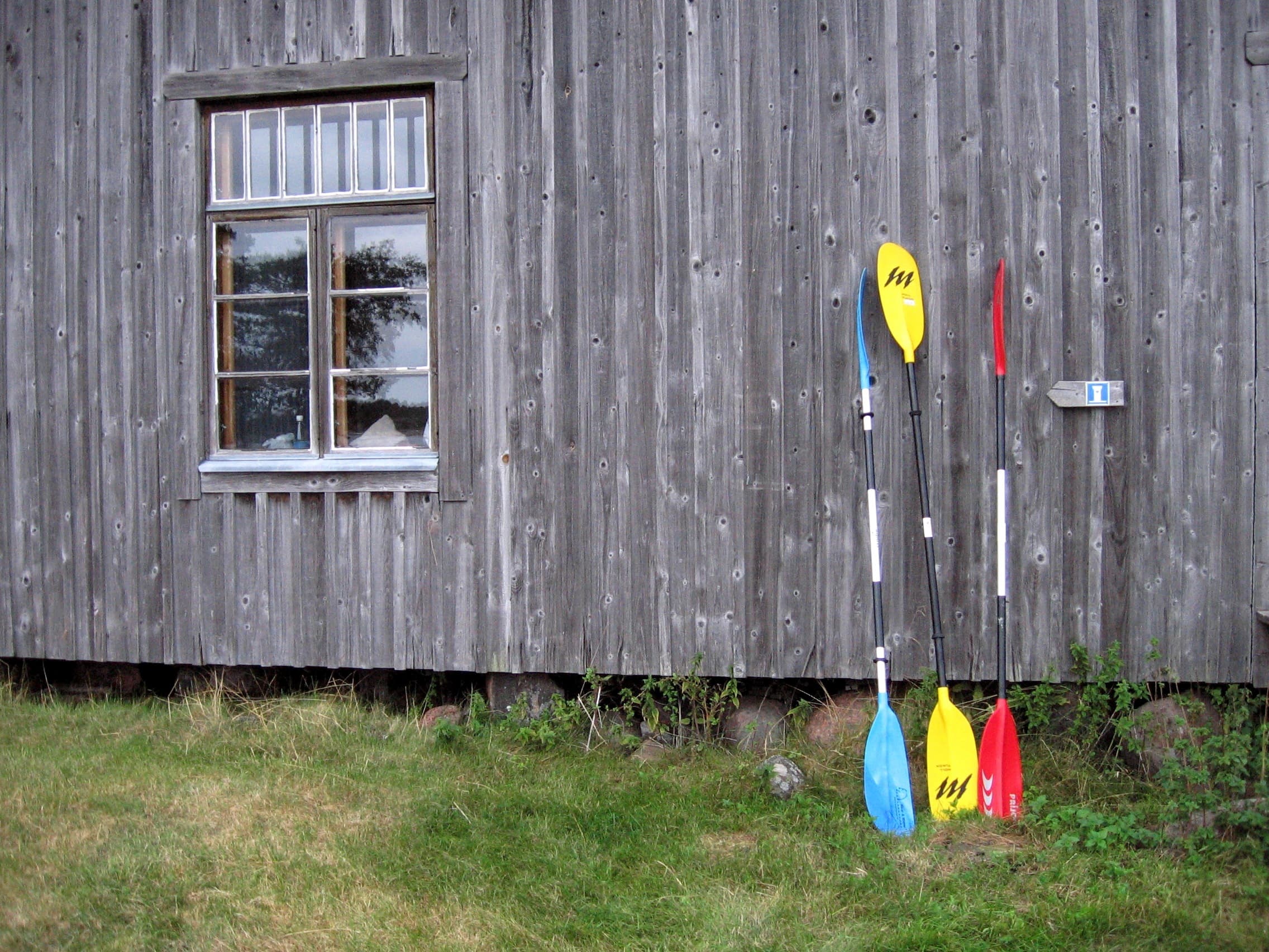 Bild: Laura Lehtonen Tre paddlar lutar mot den gamla träväggen.