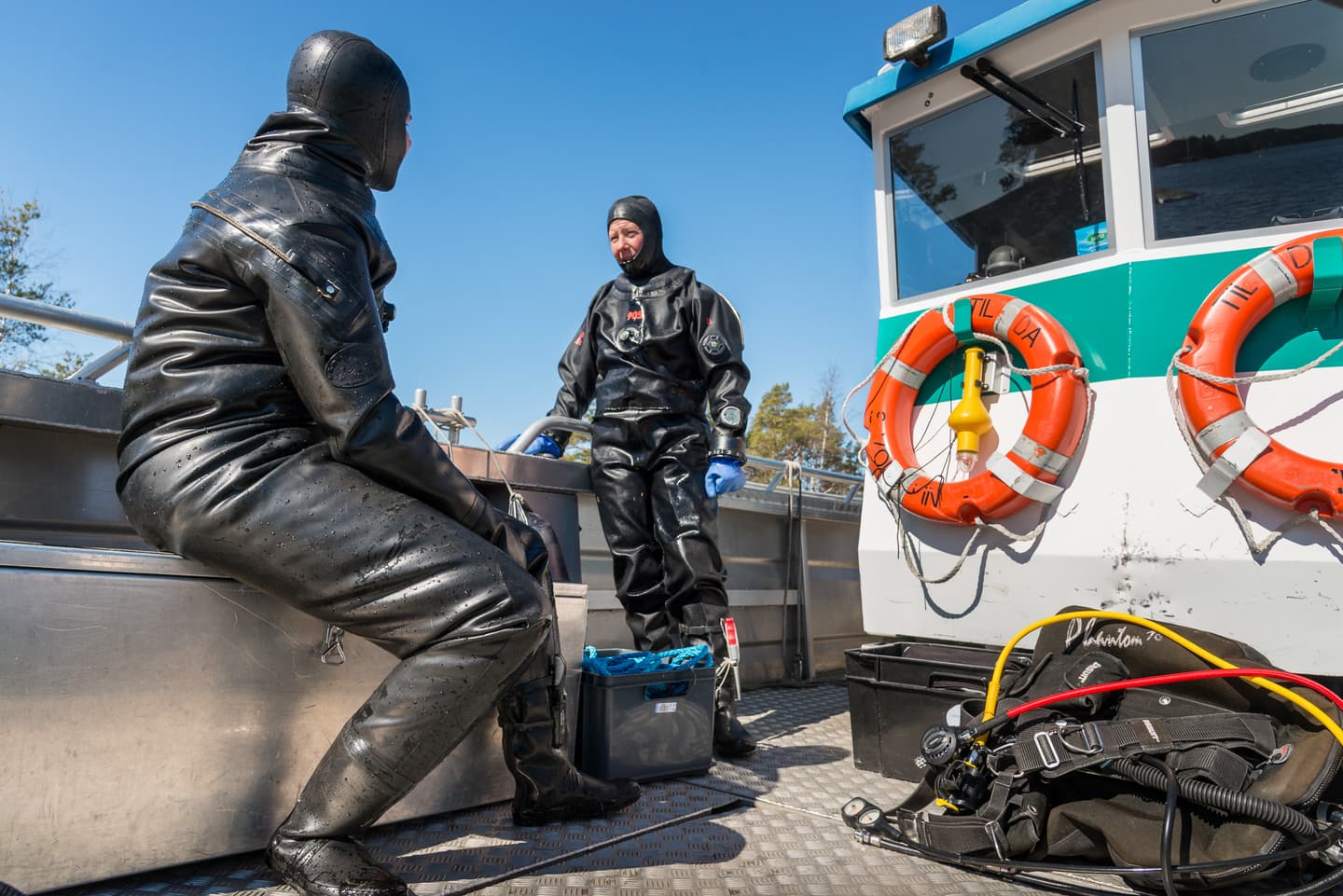 Image: Markku Tissanen People in diving suits are chatting in a boat.