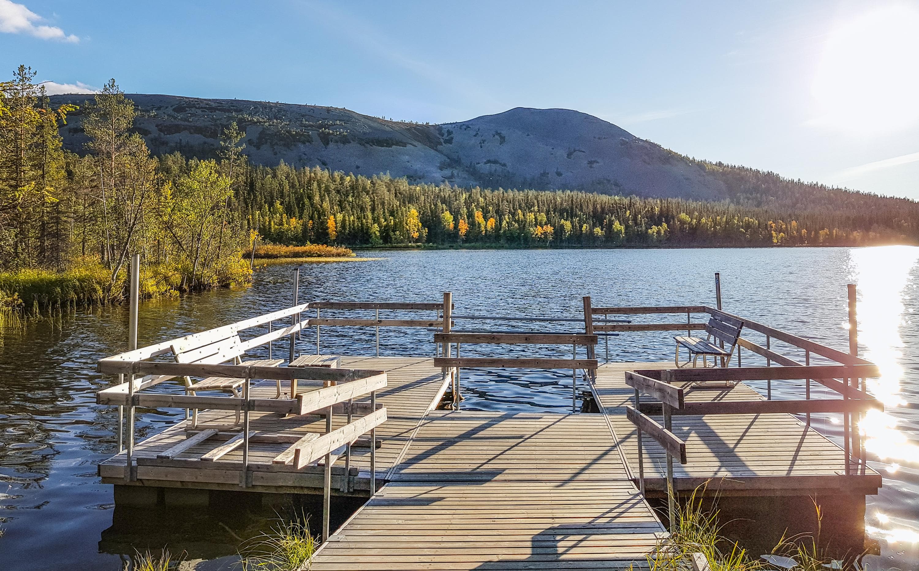 Kuva: Juuso Ritari Järven rannalla on laituri, jonka molemmilla reunoilla on penkit. Taustalla näkyy tunturin rinne, ja puissa on keltaiseksi värjäytyneitä lehtiä.