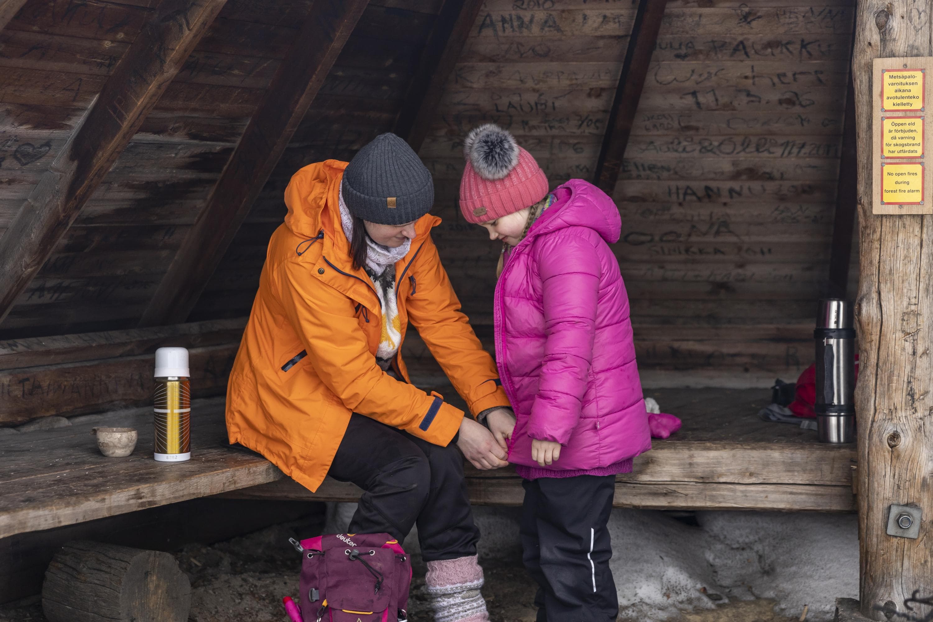 Kuva: Terhi Tuovinen Nainen pukee lapselle takkia päälle laavulla.