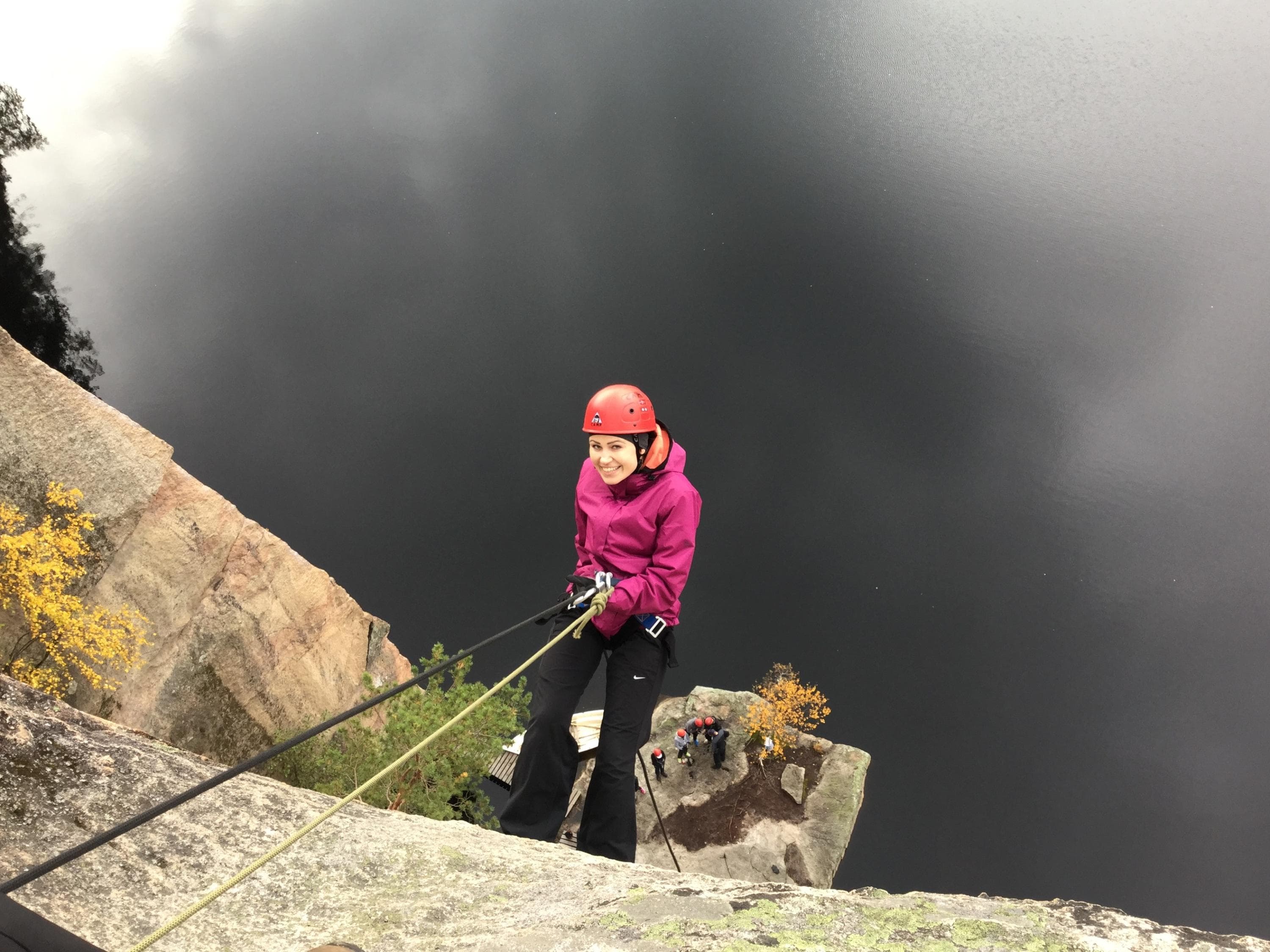 Kuva: Jaana Ahola Kypäräpäinen henkilö laskeutuu köyden varassa kallioseinämää alas. Kallion alla on järvi.