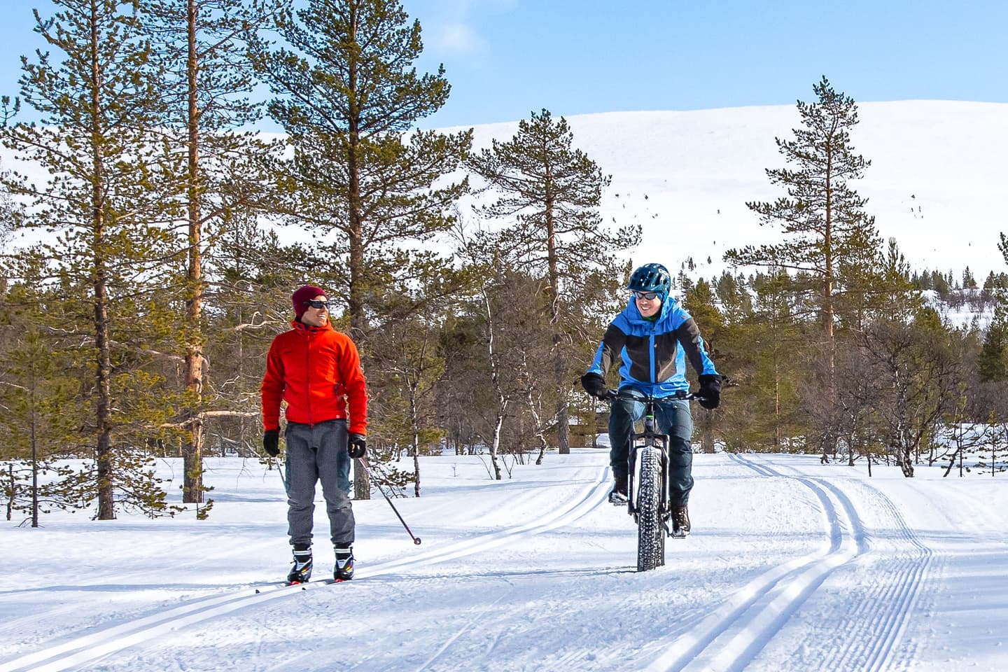 Image: Rami Valonen A skier and a cyclist on a winter trail in a sunny fell landscape.
