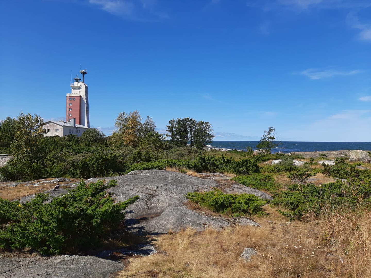 Kuva: Marjo Kekki Kallioisella saarella näkyy kaukana punavalkoinen majakka.
