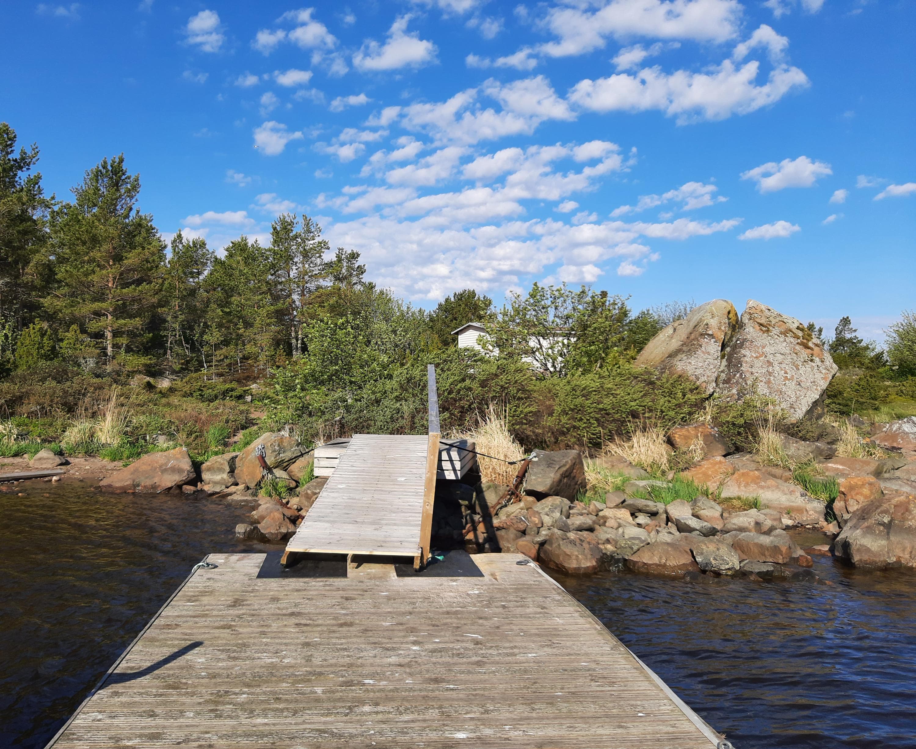 Image: Marjo Kekki A boat dock leads to the island. The shores of the island are rocky.