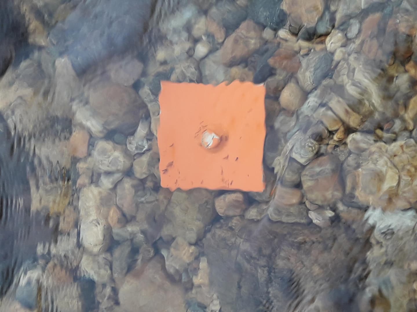 Image: Kristiina Aikio A square-shaped orange metal sign is attached to the riverbed. The signs indicate the best spot for wading across the river.