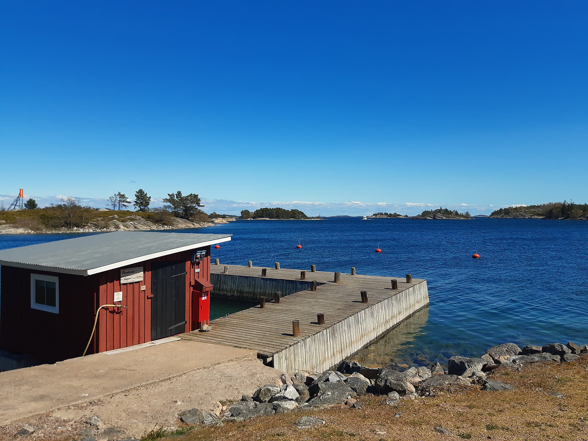 Image: Kirsi Nikkola Red wooden building and pier by the sea, islands in the background