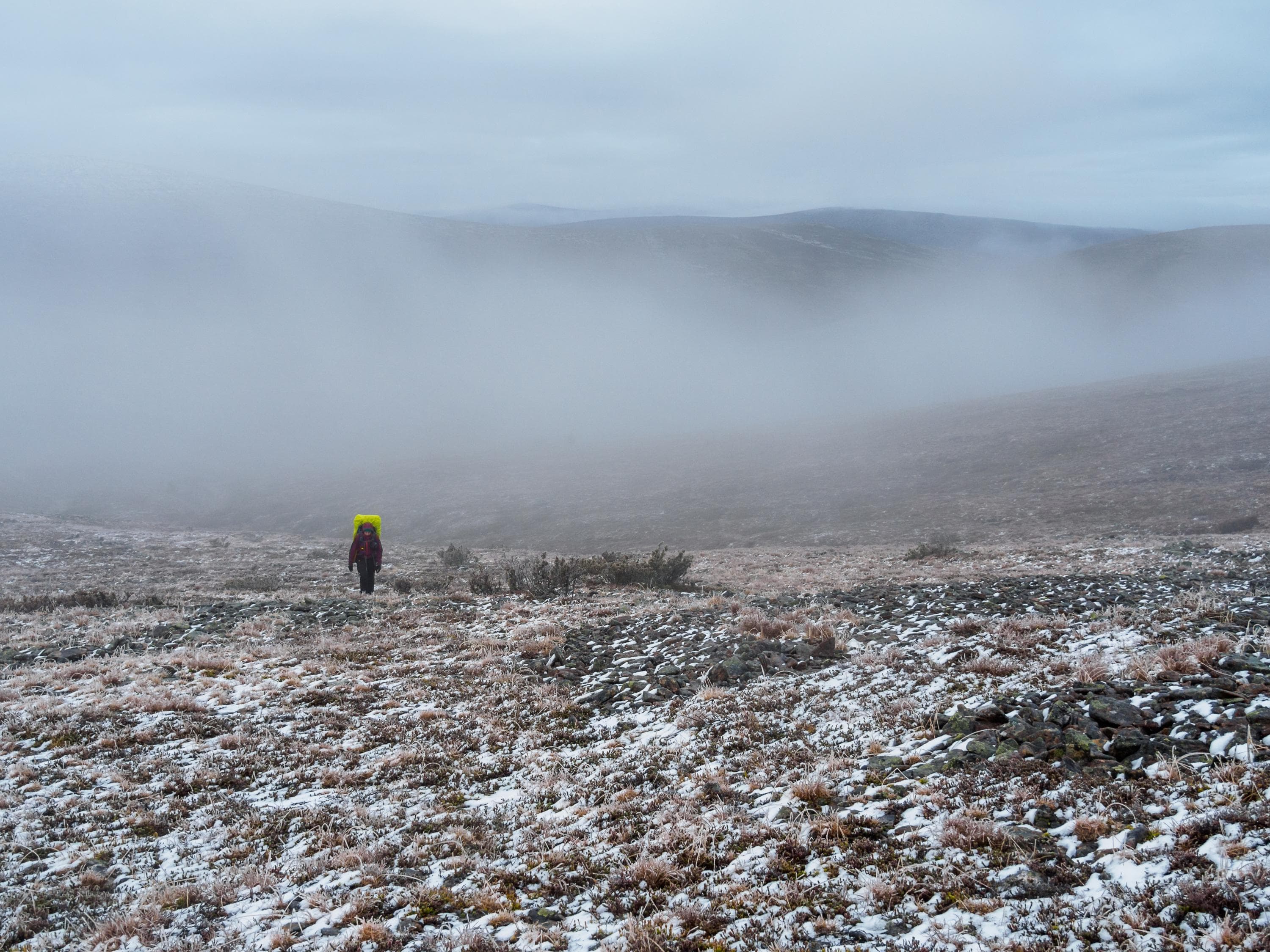 Image: Sampsa Sulonen A hiker walks up the slope of the fell. In the background, a fell covered in mist.