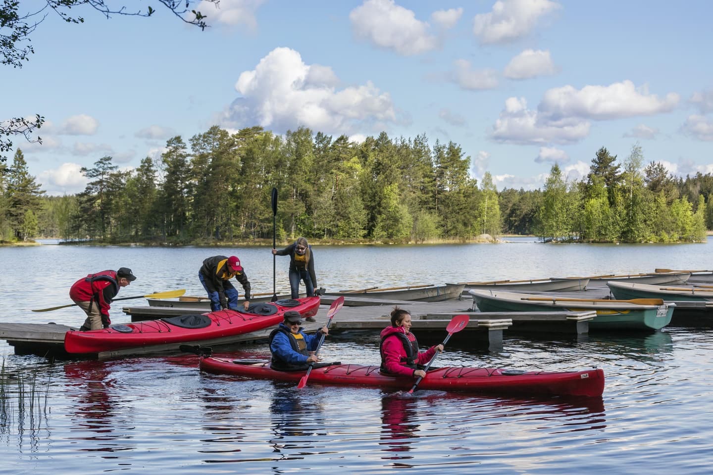 Bild: Jari Kostet Två kanoter med paddlare förbereder sig för paddling nära bryggan.