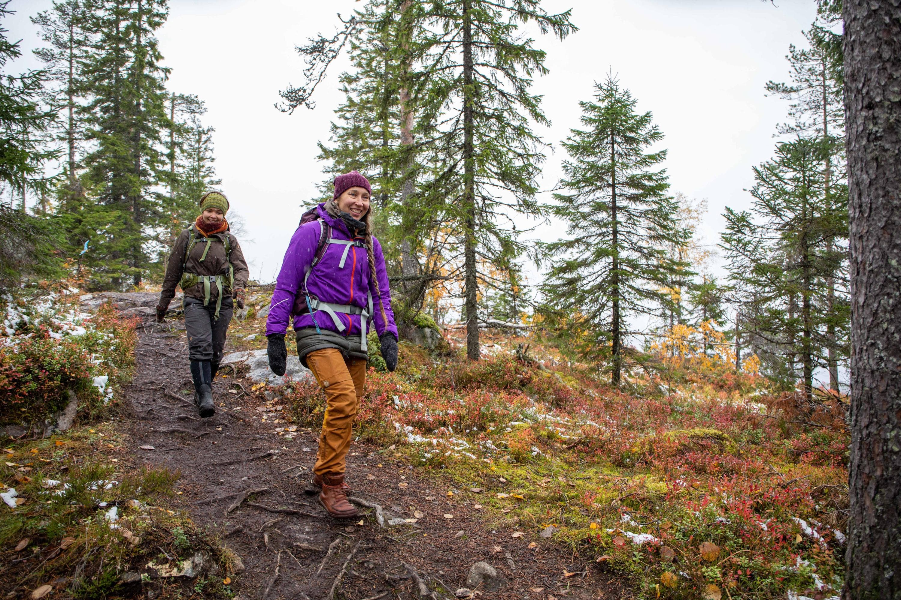Kuva: Saara Lavi Kaksi hymyilevää retkeilijää syksyisellä metsäpolulla.