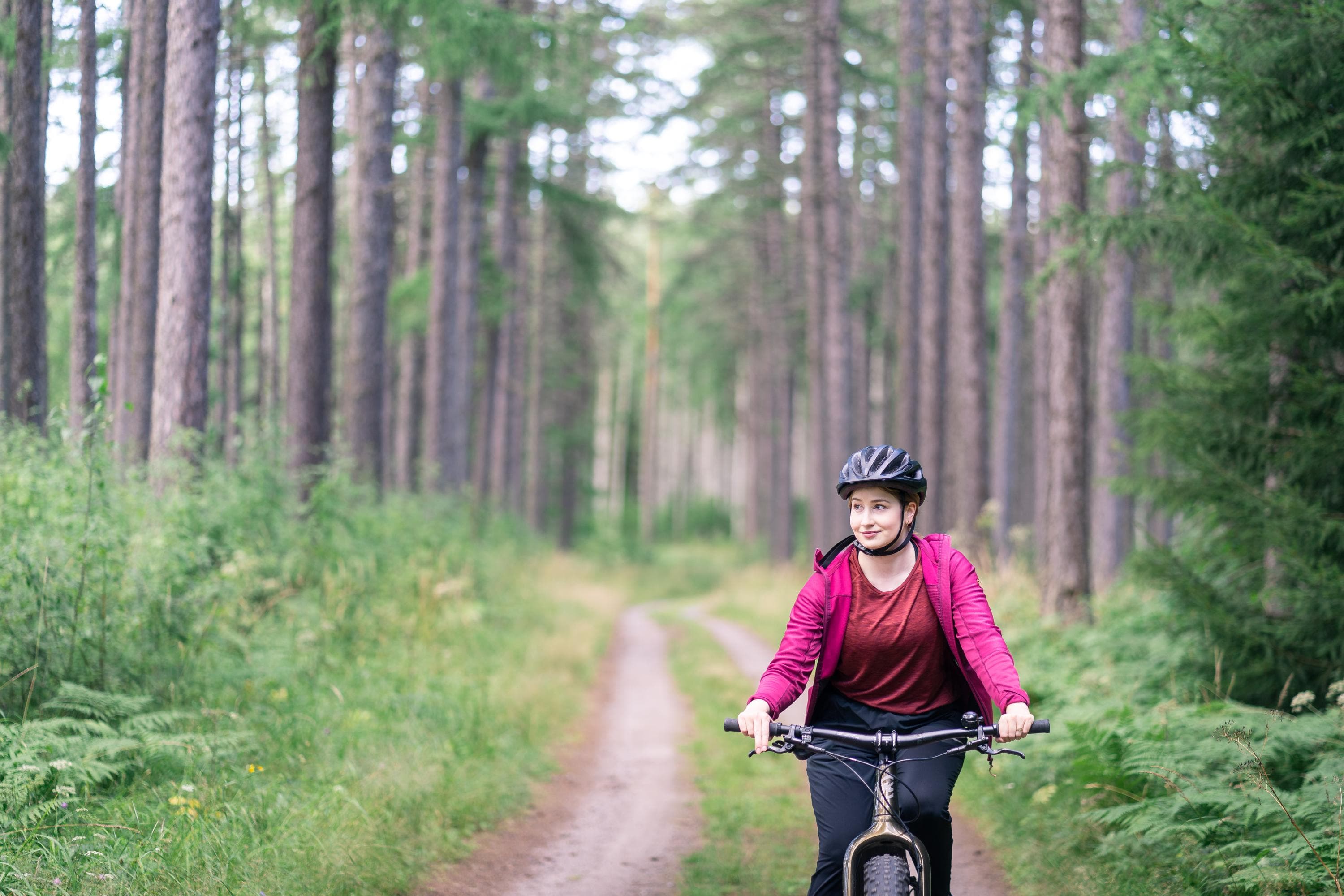 Bild: Mitja Piipponen En cyklist på en grusväg. Höga träd i bakgrunden.