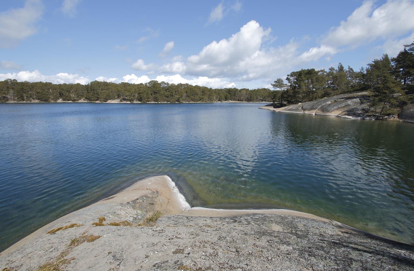 Image: Jussi Helimäki Cliffs, further back wooded cliffs on the shores of a calm bay.