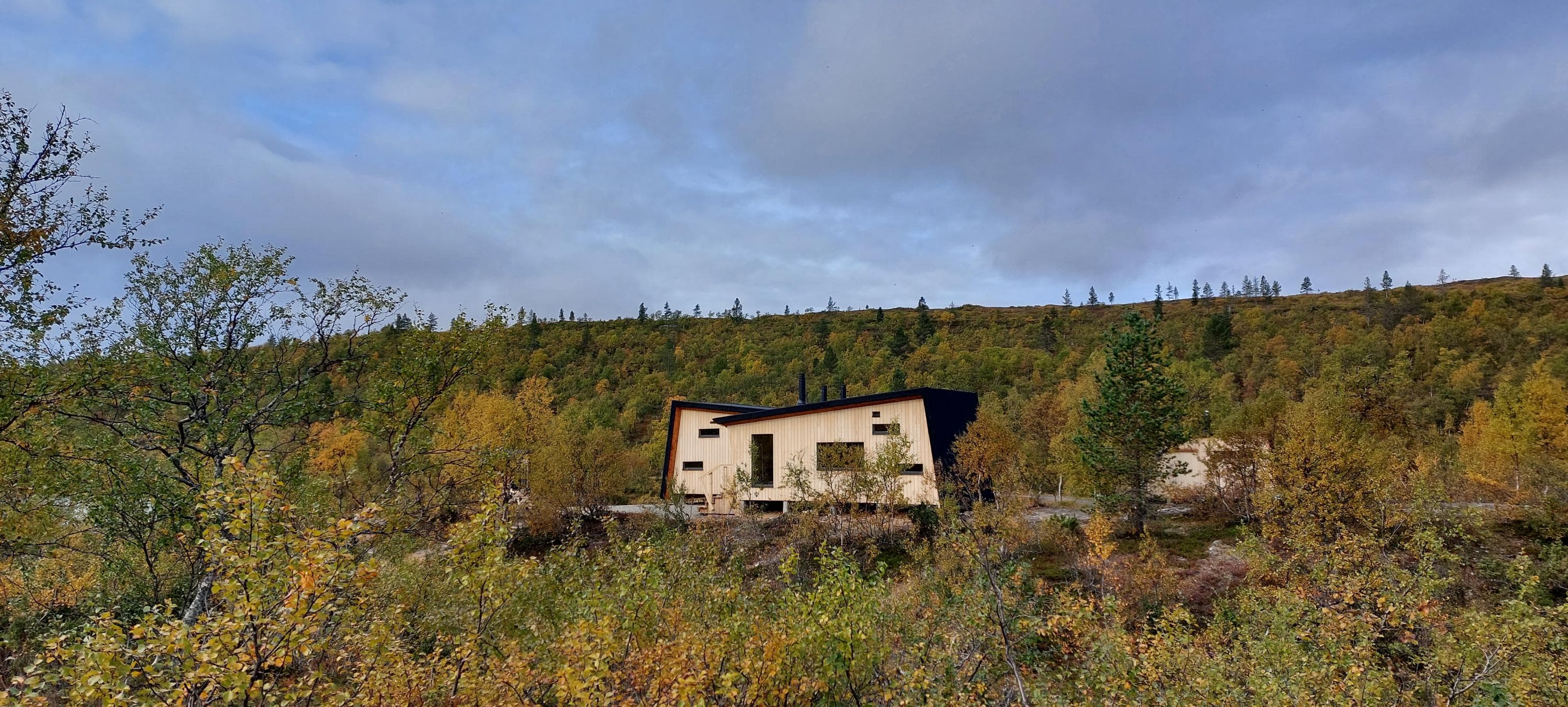 Kuva: Maria Makkonen Tunturikoivun lomasta näkyy moderni ja puinen tupa.