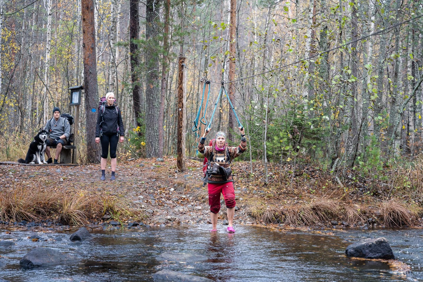 Bild: Mitja Piipponen En vandrare korsar floden med hjälp av en vadningsvajer. Andra väntar i bakgrunden på sin tur.