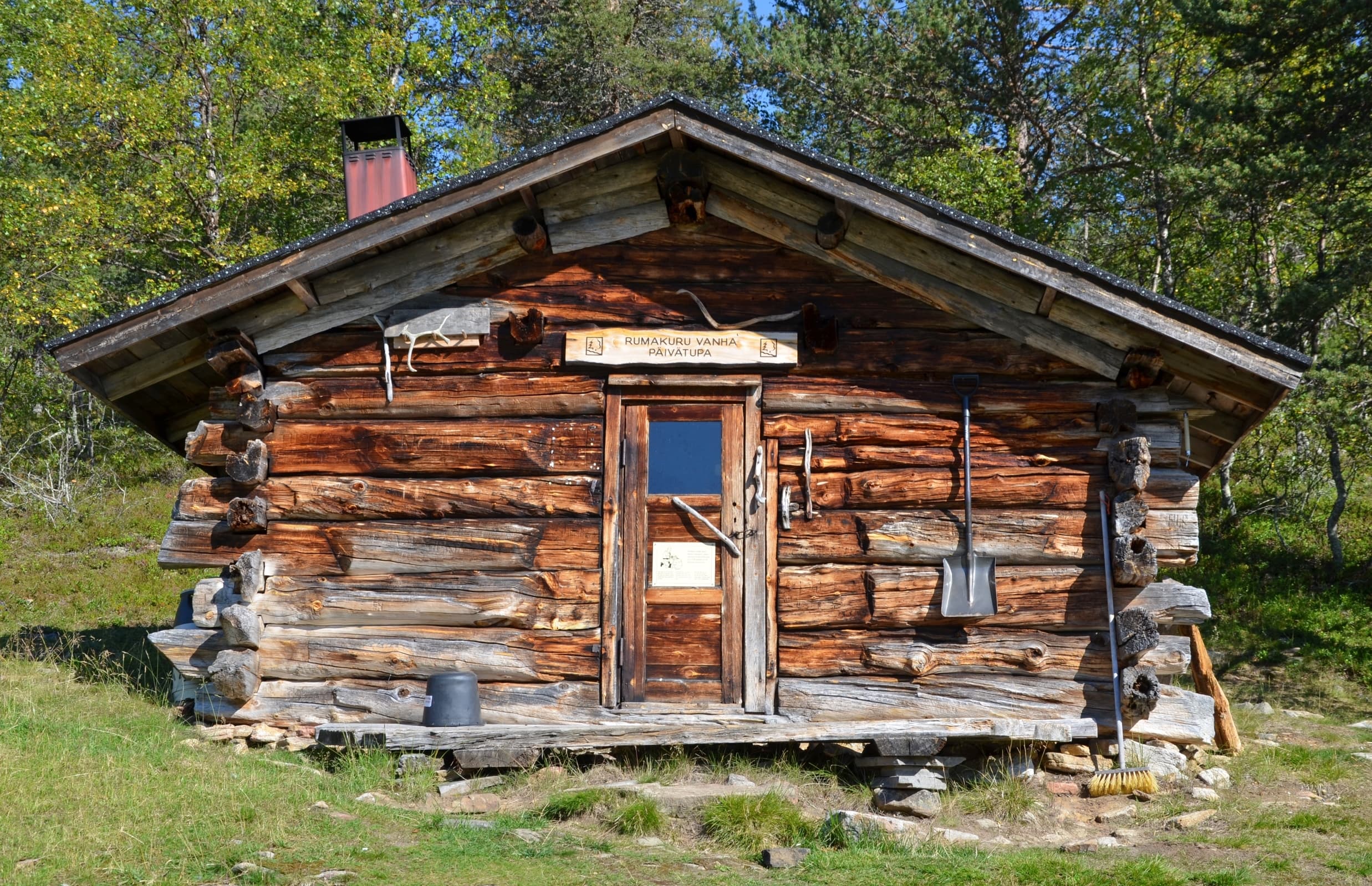 Image: Pasi Nivasalo Old cabin in the sunshine. There is green grass around the cabin.