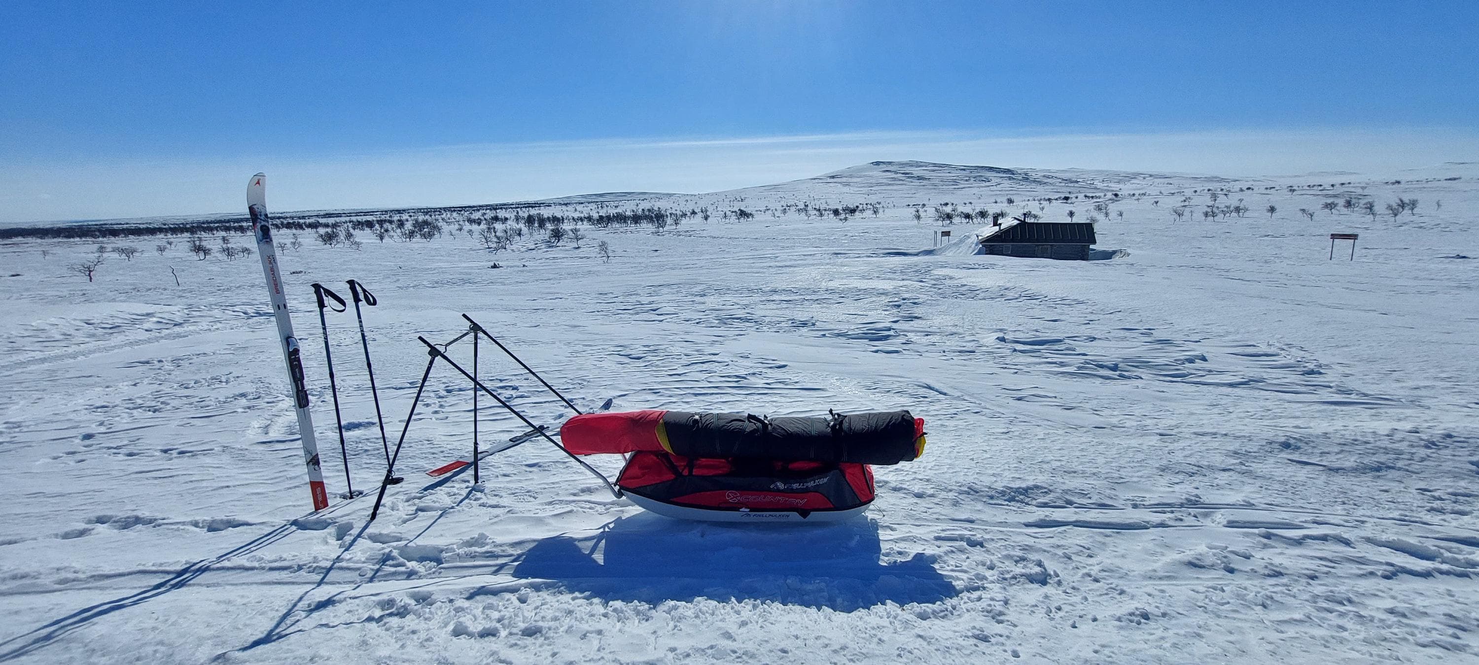Image: Maria Makkonen A ski touring pulka packed in the snow. The sun is shining in the spring weather with a clear sky.