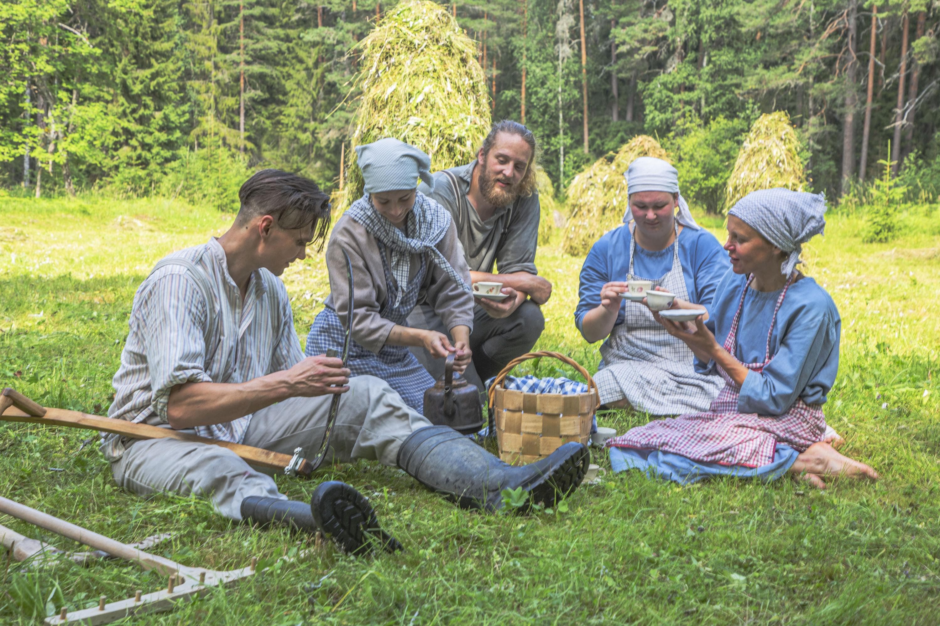 Bild: Seppo J Rantala Människor klädda i gammaldags kläder sitter på ängen och äter snacks
