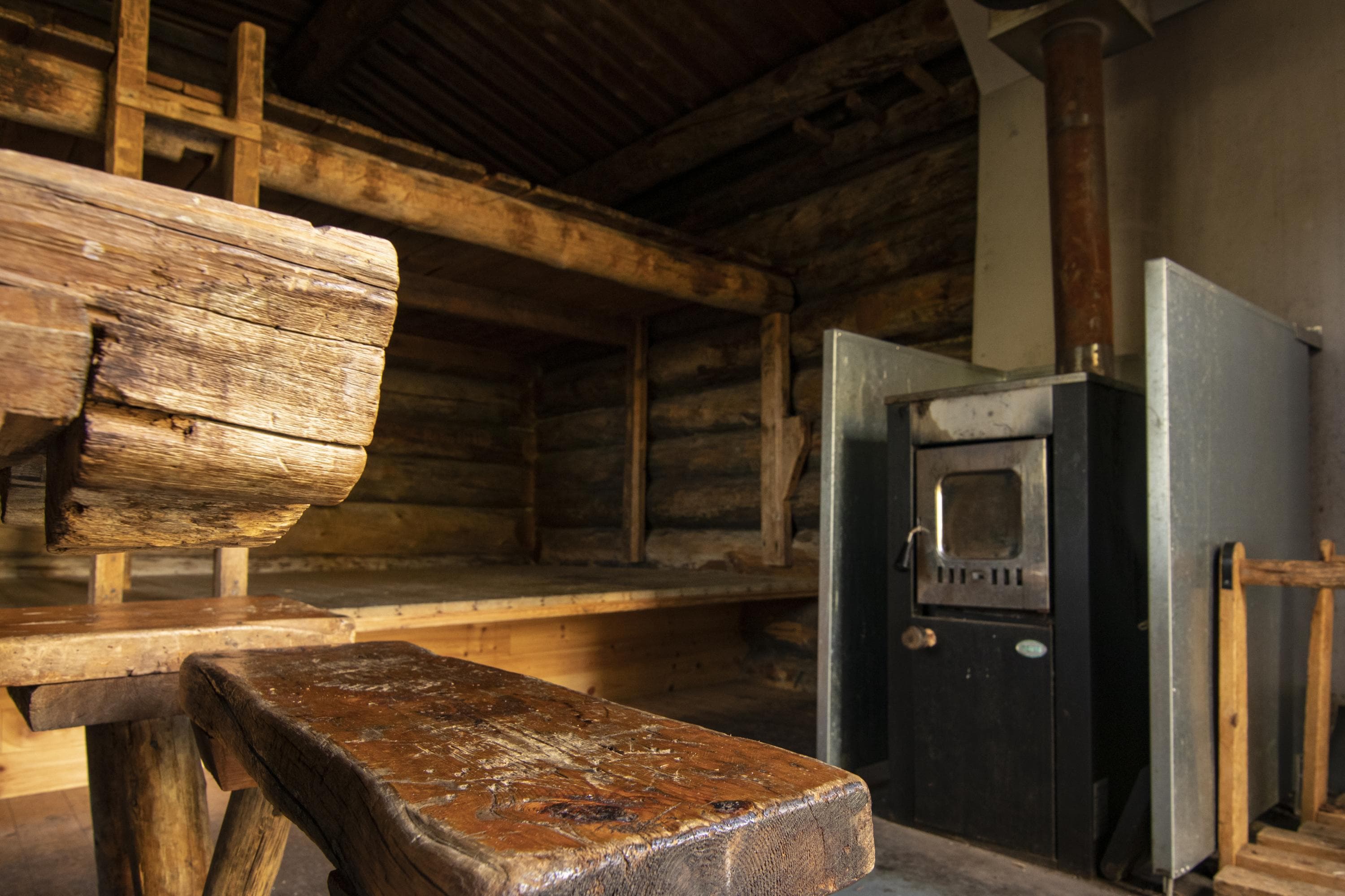 Image: Jonna Kalliomäki Inside the hut: a stove, a table, and a bed.