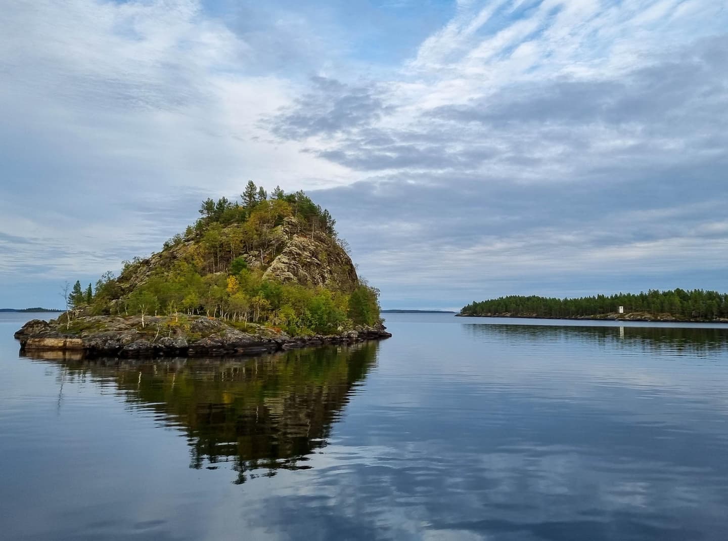 Kuva: Kirsi Ukkonen Muurahaiskeon muotoinen saari peilautuu tyynen vedenpintaan.