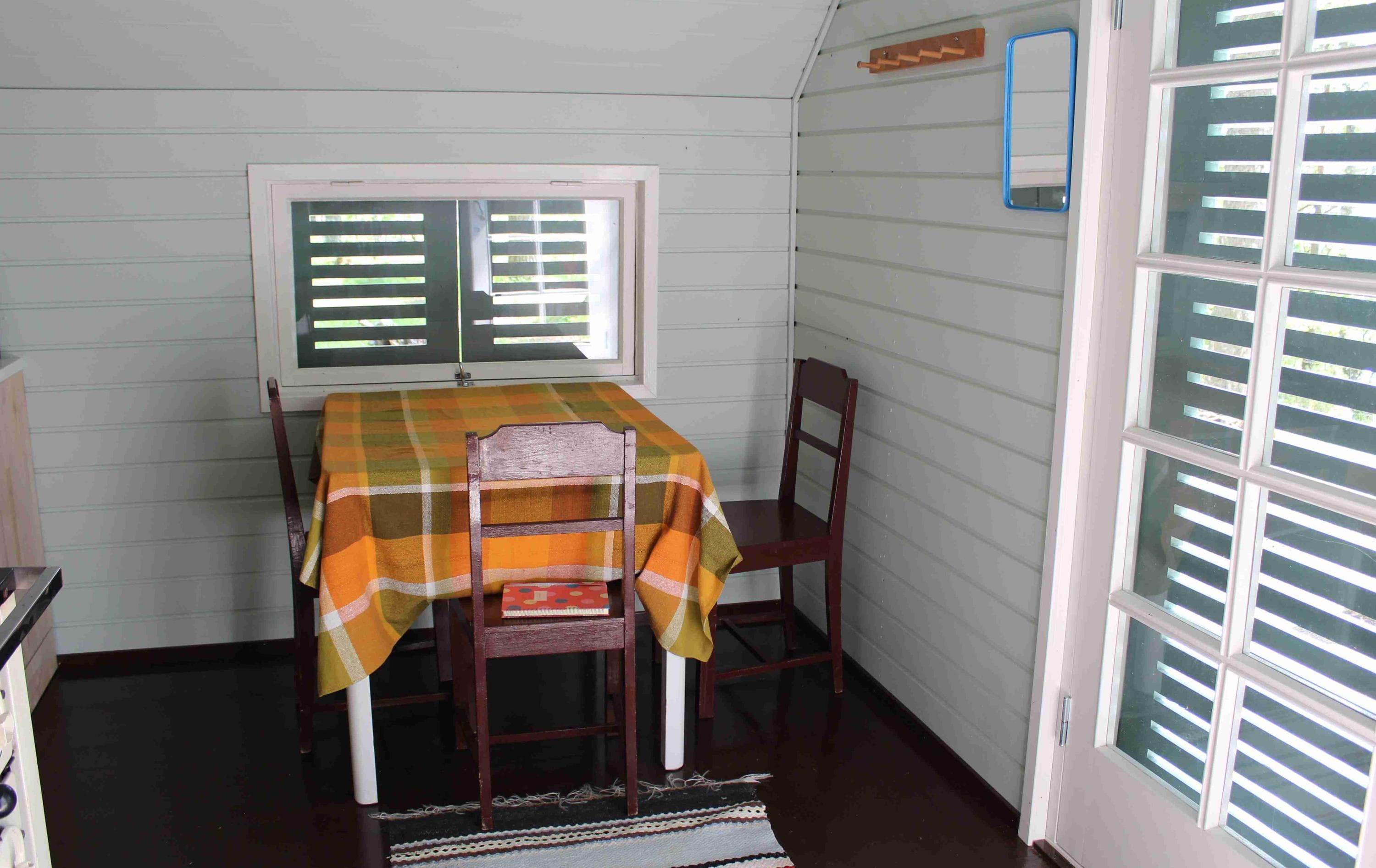 Kuva: Päivi Tervonen. Keskellä kuvaa ruokapöytä, jonka ympärillä tuoleja. Pöydän takana ikkuna. Kuvan oikeassa reunassa ovi.