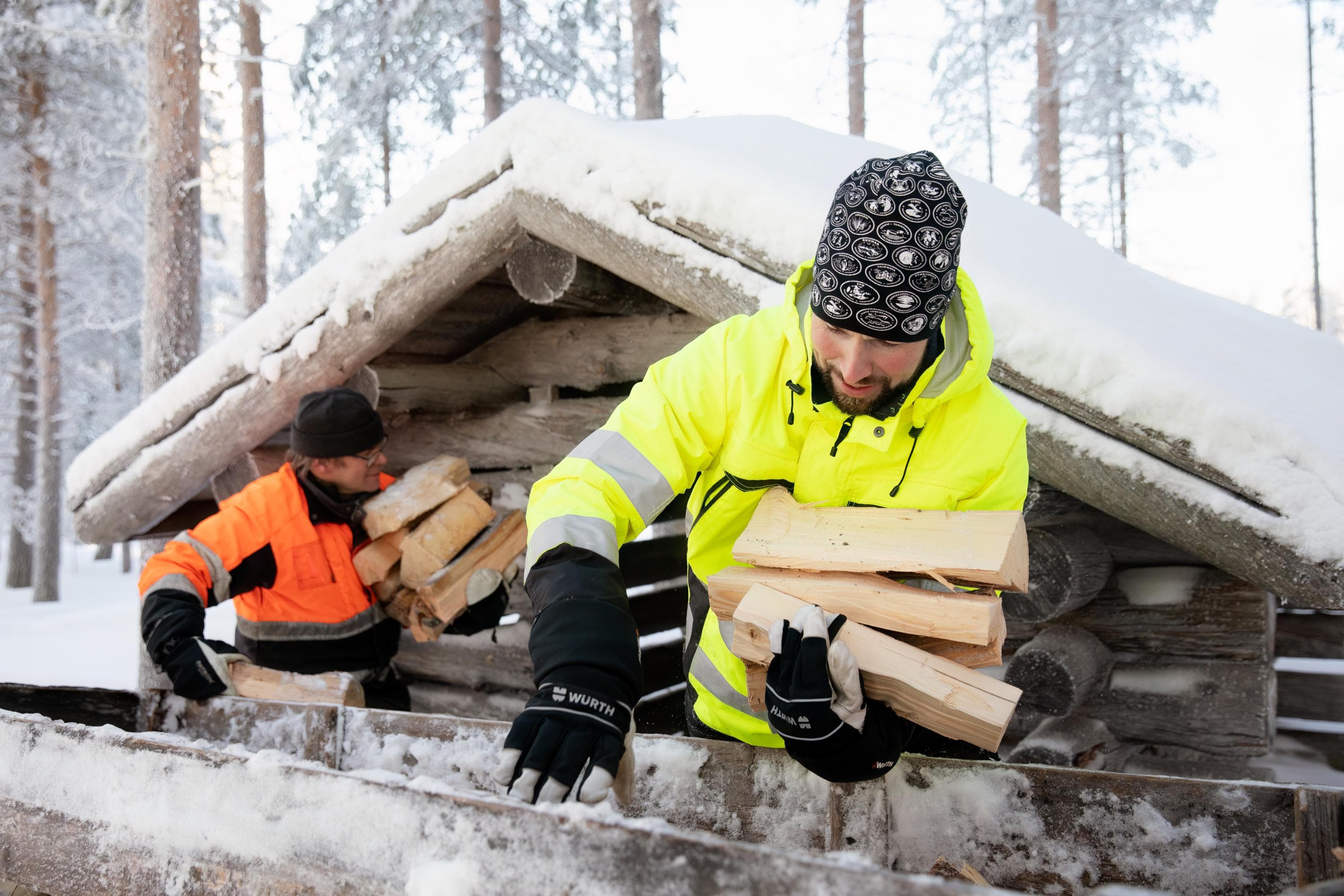 Kuva: Kuvatoimisto Keksi Kaksi mieltä purkavat polttopuita kelkasta puuvajaan talvella.