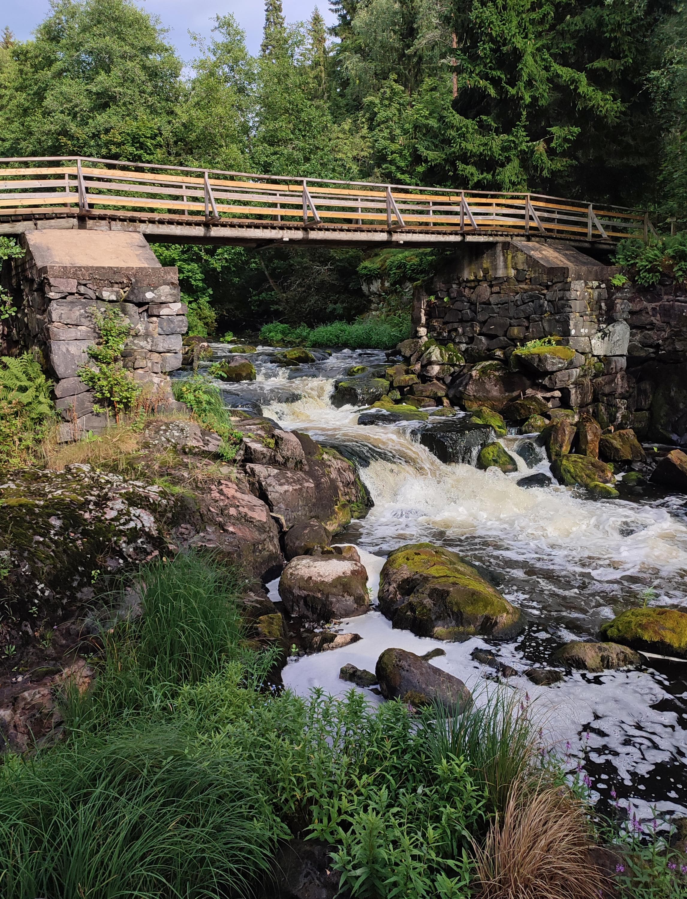Kuva: Jussi Helimäki Puinen kävelysilta ylittää kuohuvan kosken.