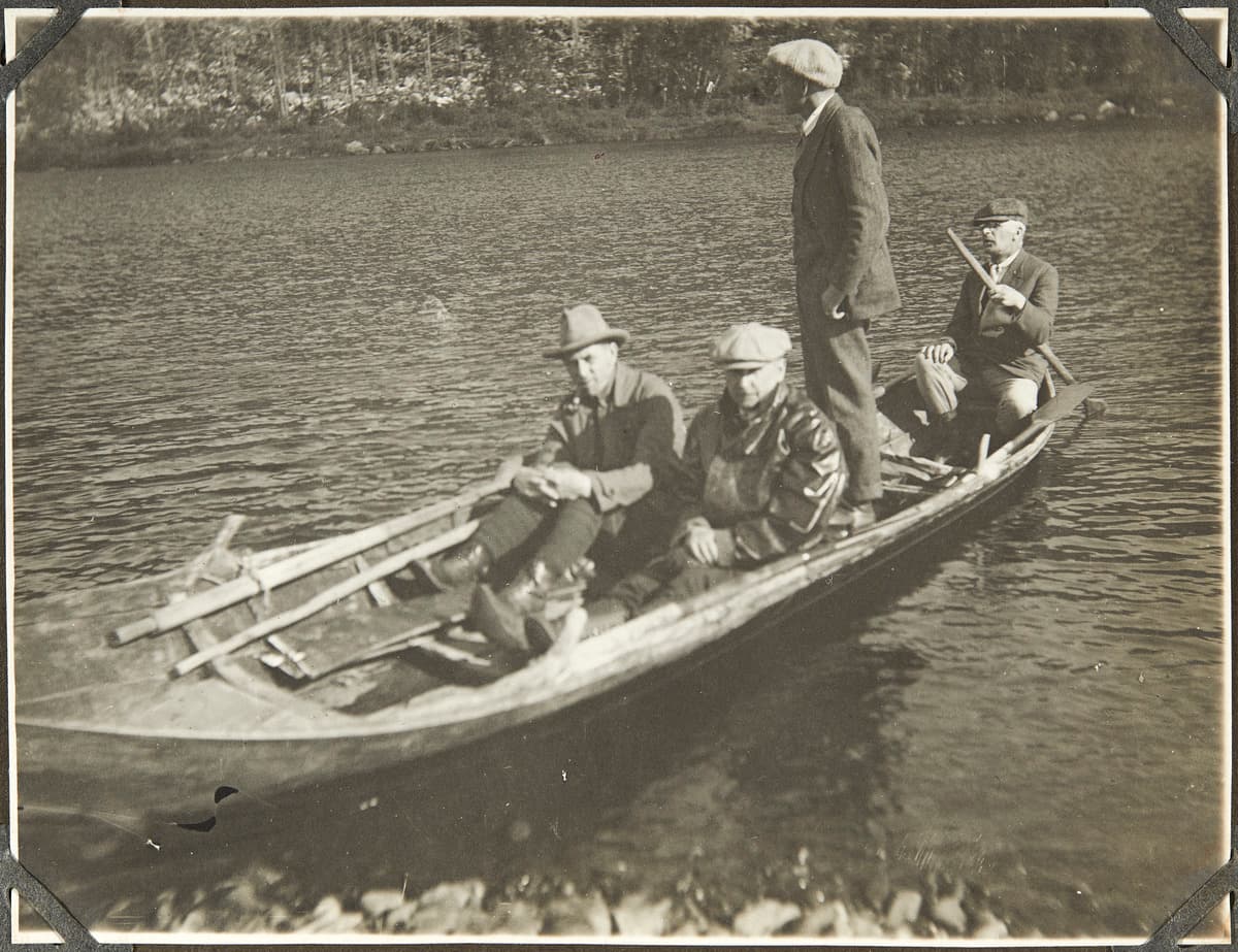 Kove: Mikkola Erkki / Museovirasto, kansatieteen kokoelma There are four people in a boat by the river, one of whom is standing.