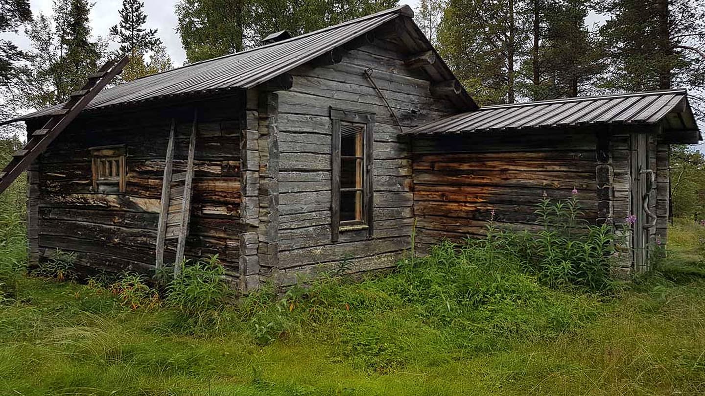 Image: Ninni Raasakka A gray log building in poor condition. Coniferous trees grow in the background.