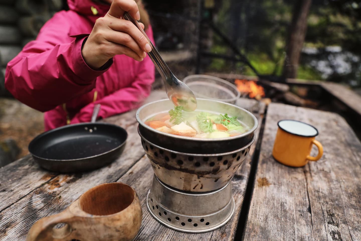 Image: Harri Tarvainen A hiker is stirring food cooking on a portable camp stove.